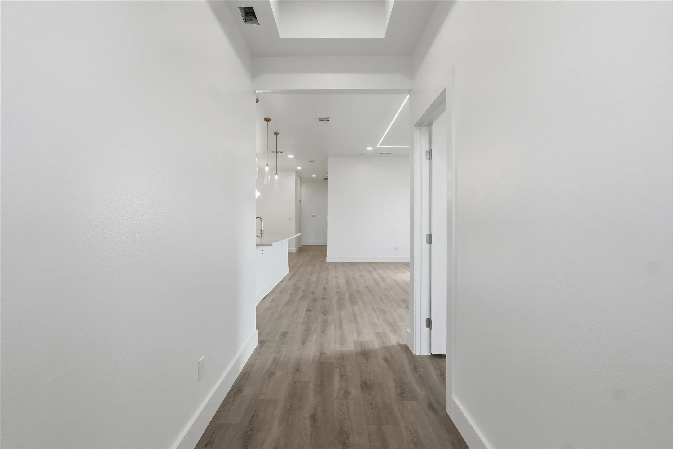 Wood-finish flooring throughout, recessed lighting, and a white countertop with pendant lighting