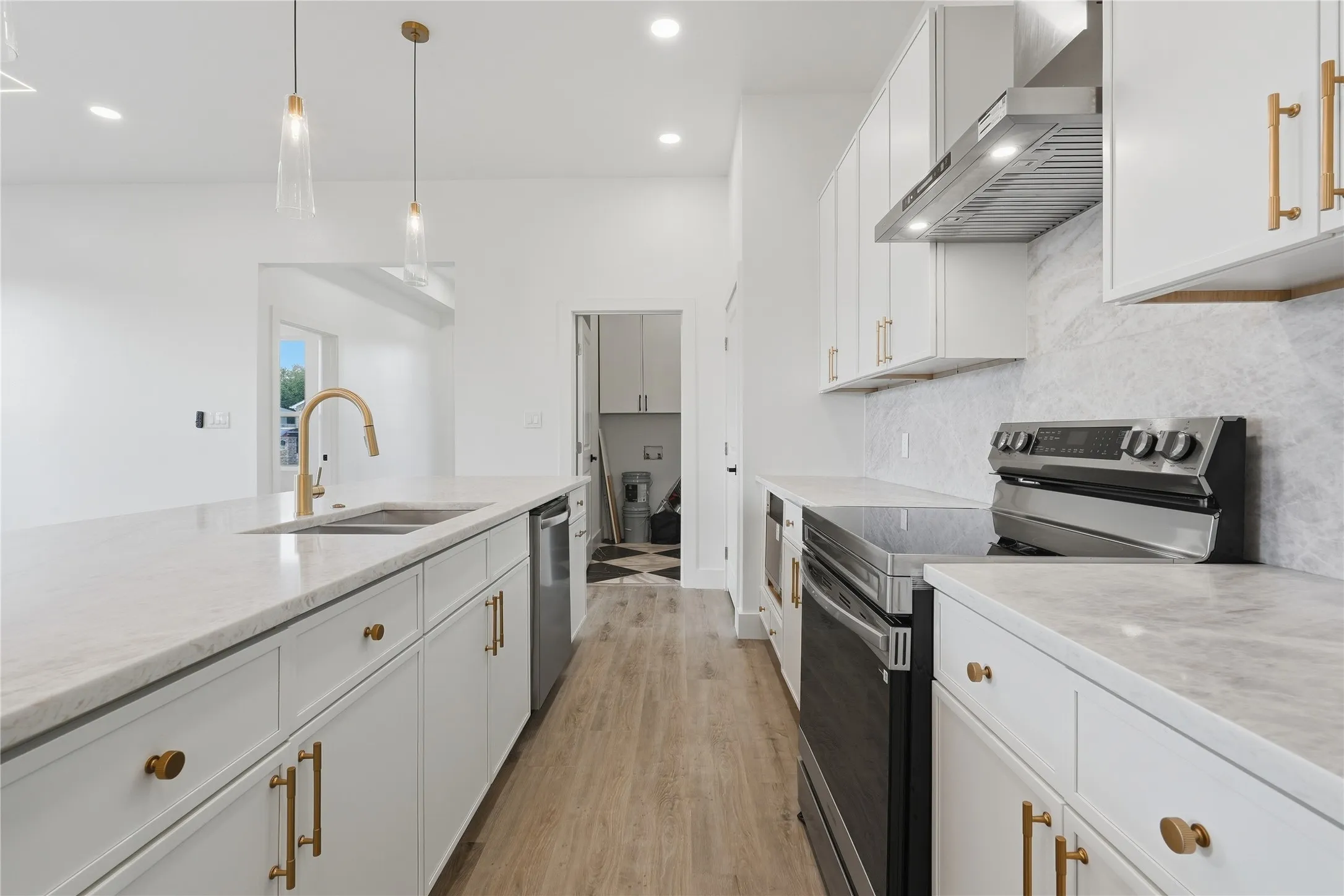 Contemporary kitchen featuring white cabinetry, light-toned countertops, stainless steel appliances, and wood-finish flooring