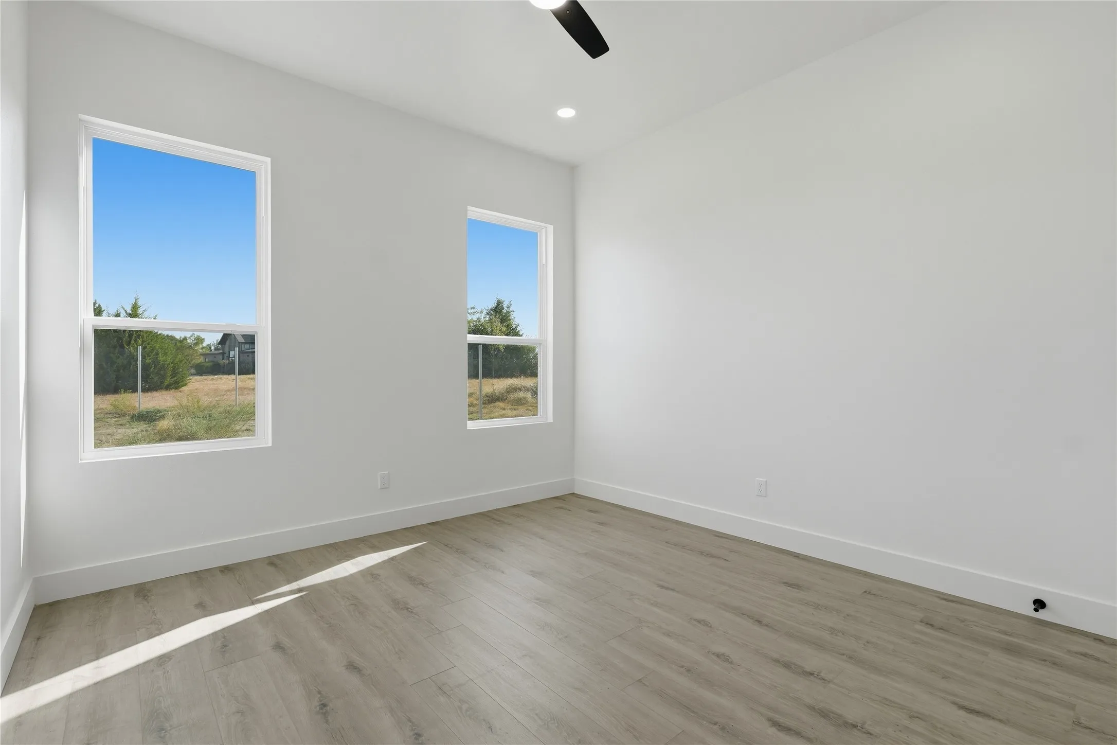 Recessed lighting, ceiling fan, wood-finish flooring, two windows, and white walls