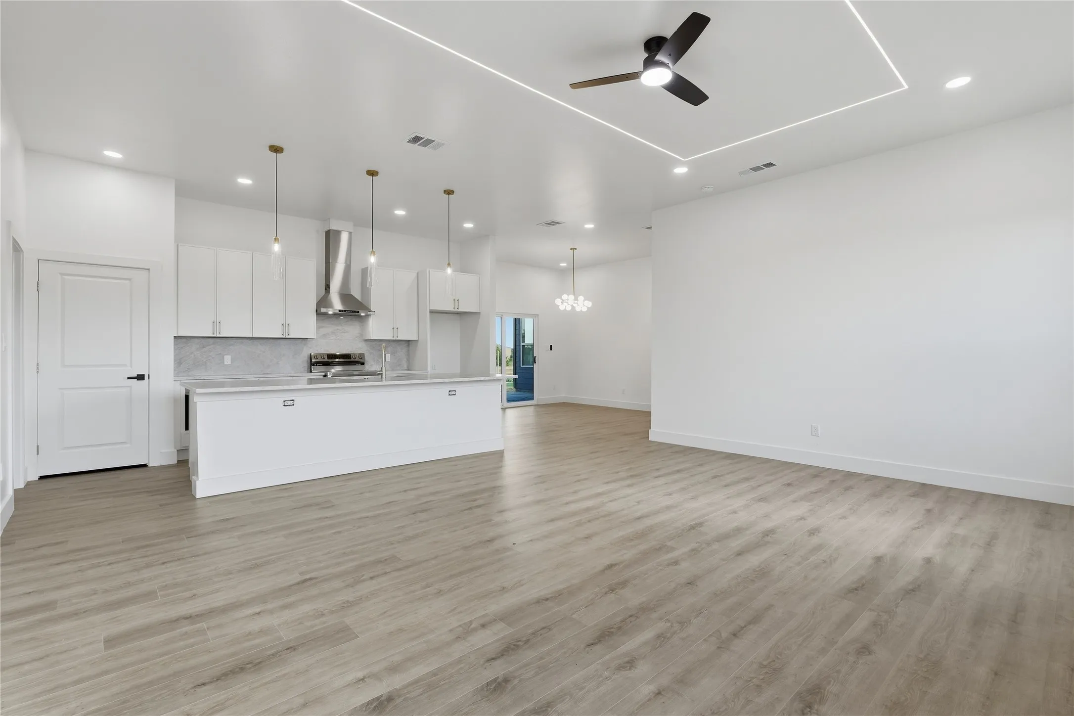 Open-concept living area featuring light wood-finish flooring, recessed lighting, and a modern ceiling fan