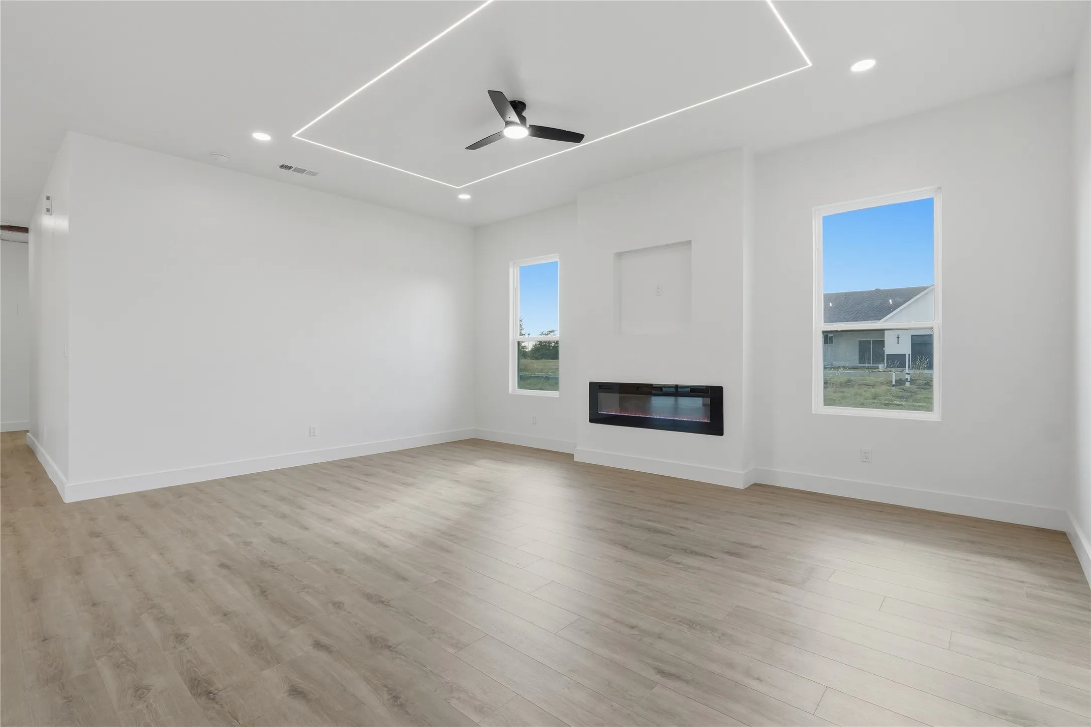 Spacious room with wood-finish flooring, recessed lighting, and a contemporary ceiling fan
