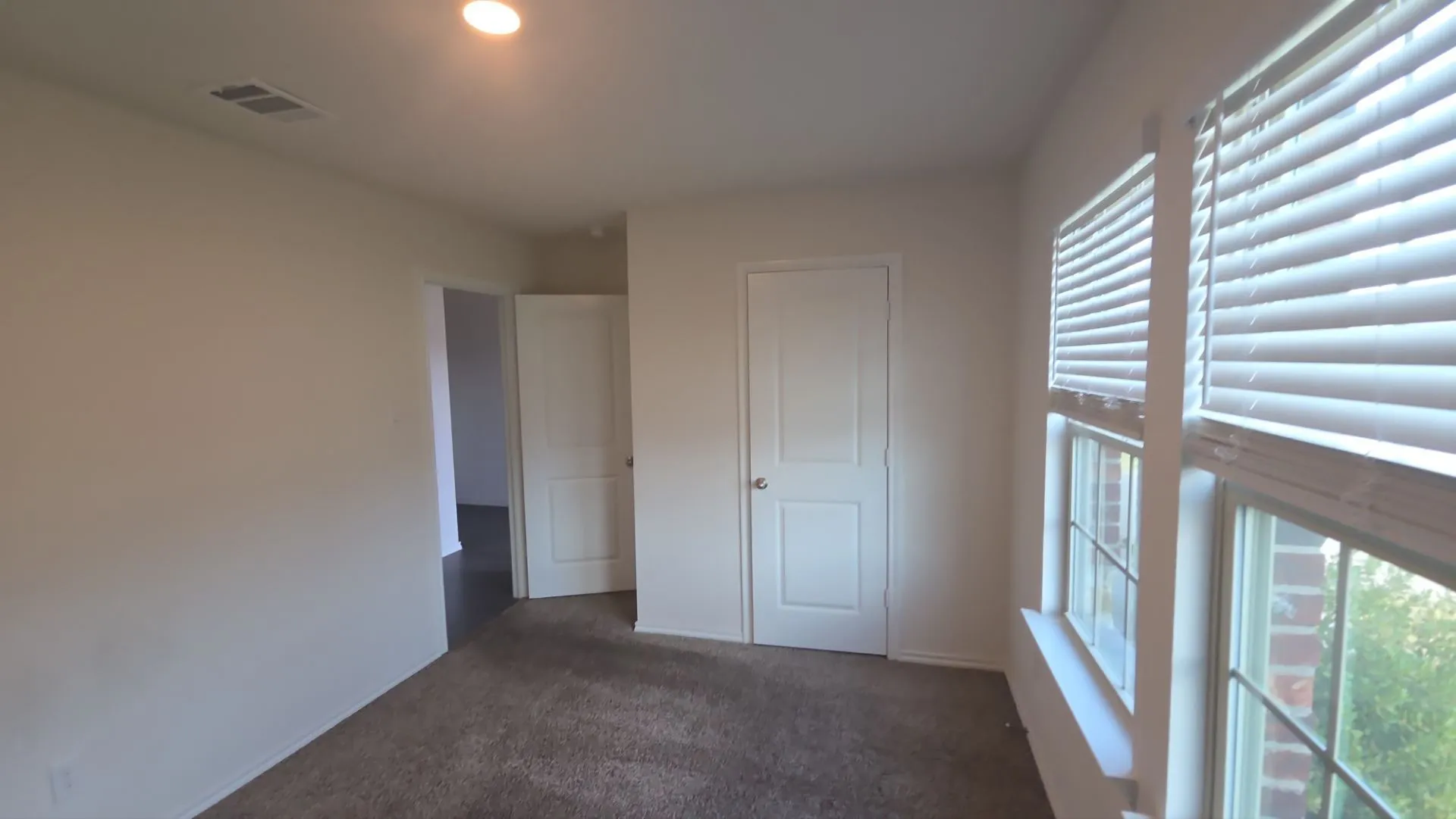 Recessed ceiling light, carpeted flooring, two paneled doors, and two windows with blinds