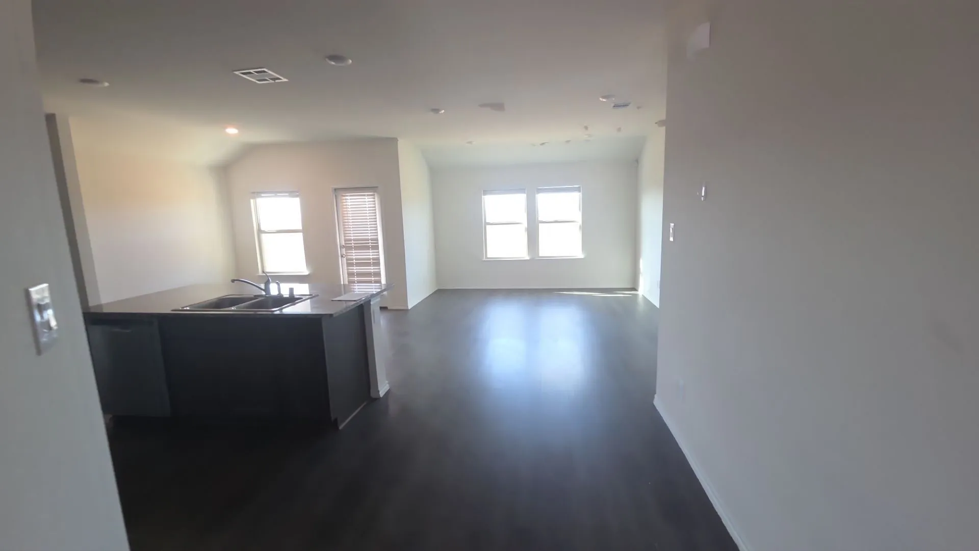 Spacious open-concept layout featuring dark wood-finish flooring, recessed lighting, and ample natural light from multiple windows