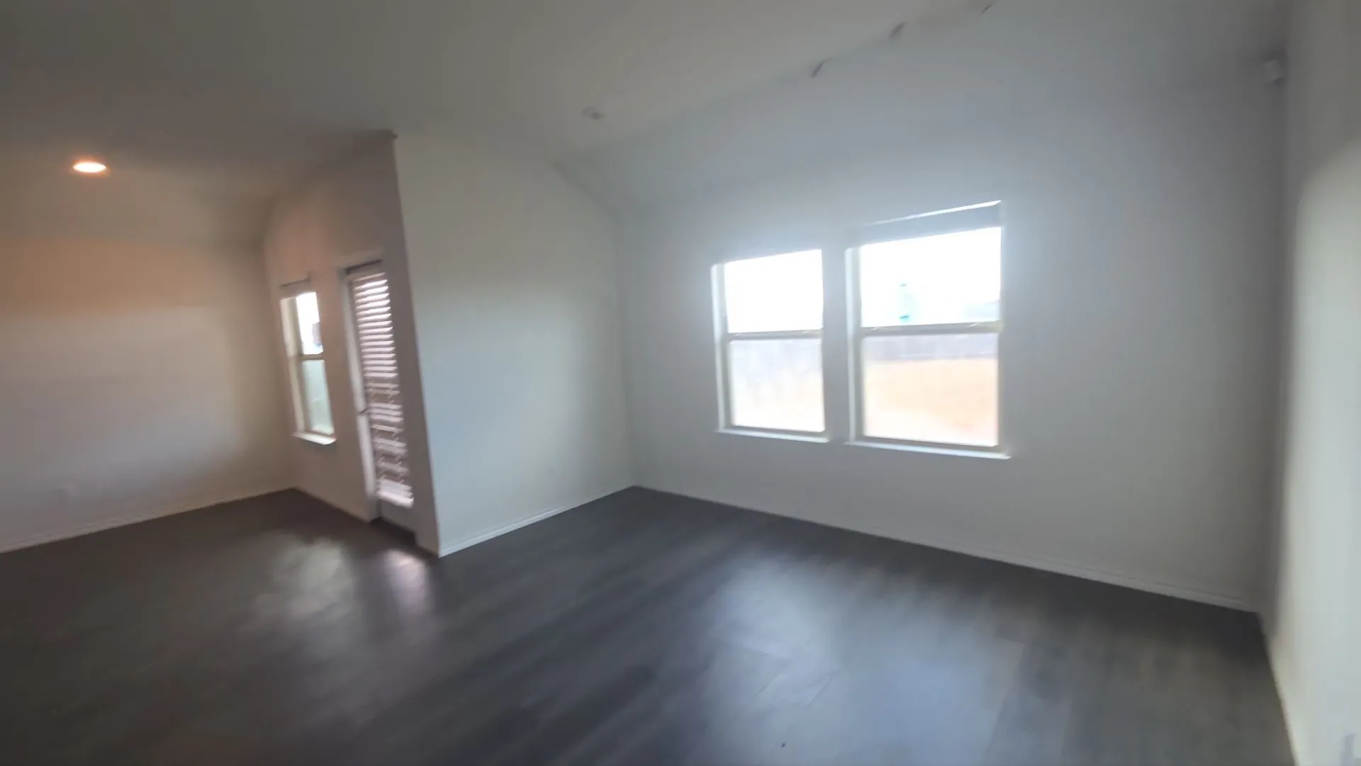 Recessed lighting, wood-finish flooring, multiple windows, and a glass-paneled door