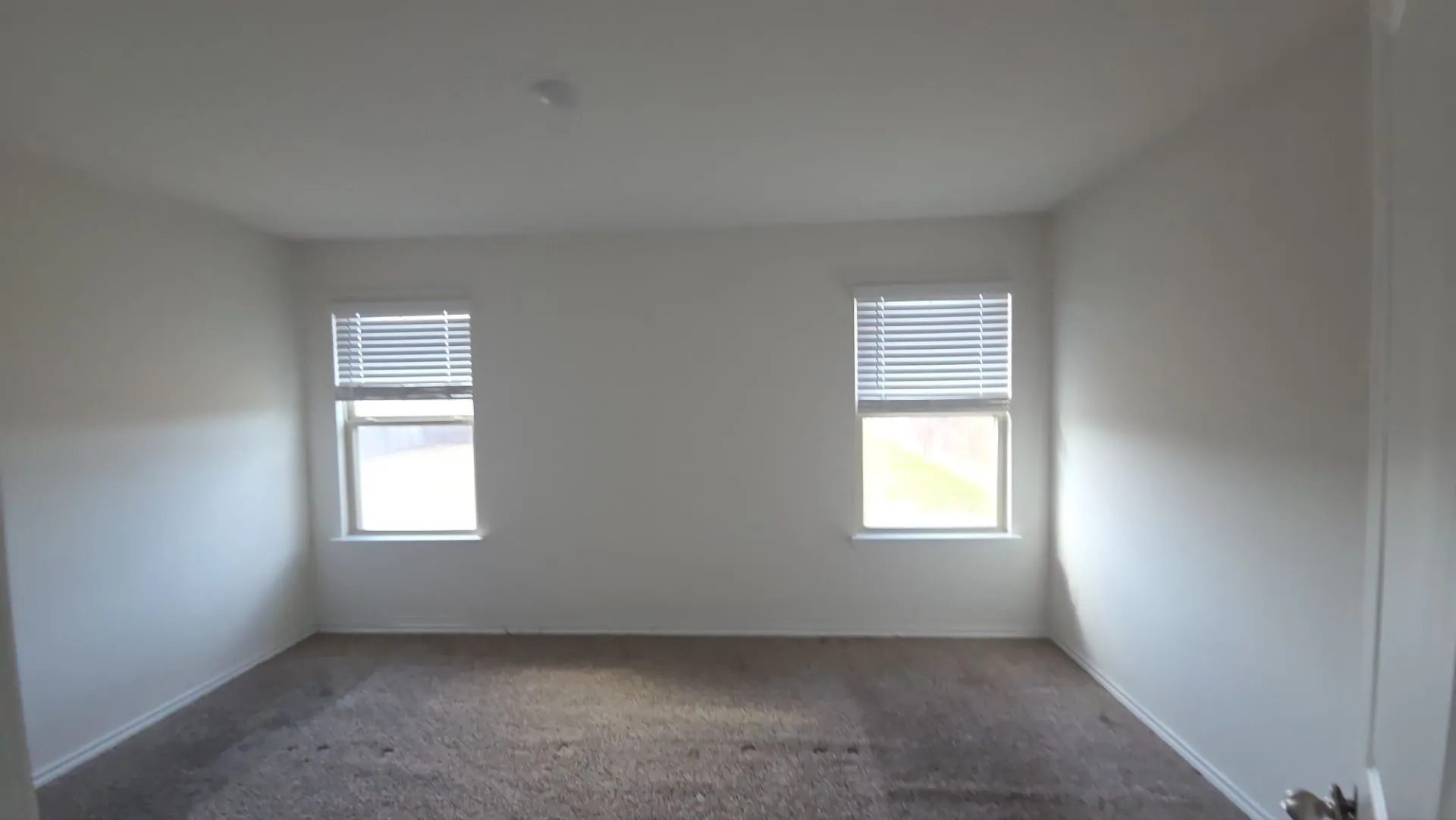 Neutral wall color with two windows, each featuring horizontal blinds