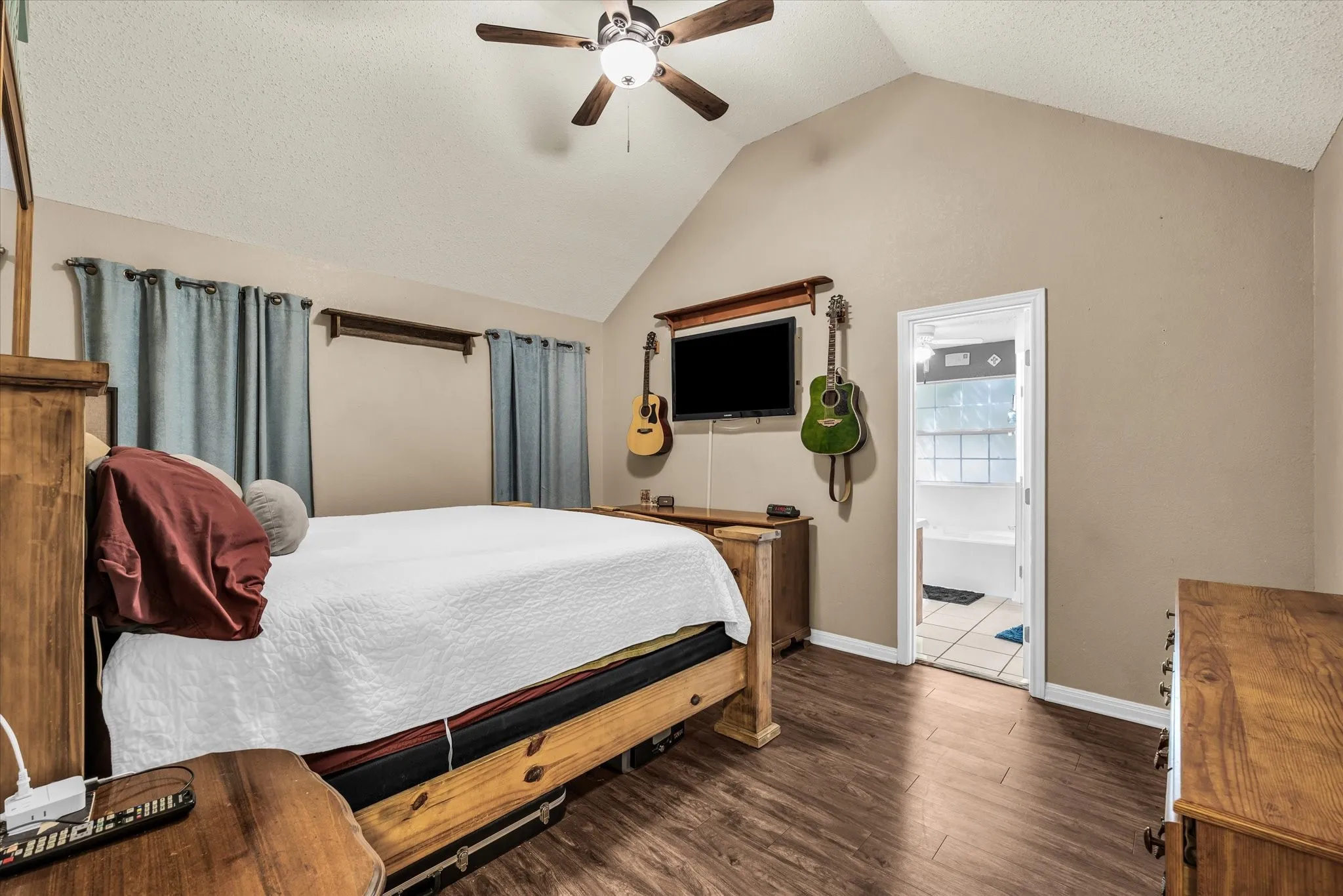 Vaulted ceiling with a ceiling fan, wood-finish flooring, and light-toned wall paint