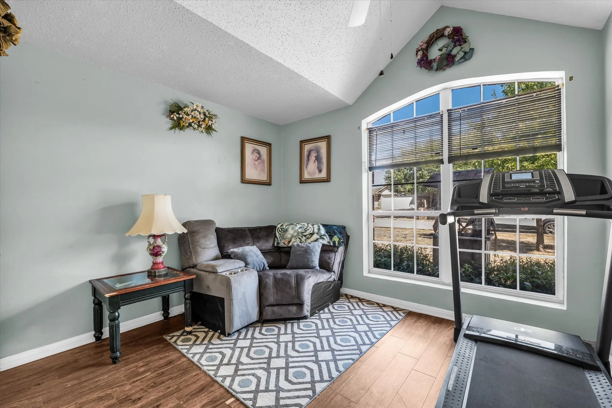 Vaulted ceiling, wood-finish flooring, arched window, and overhead ceiling fan