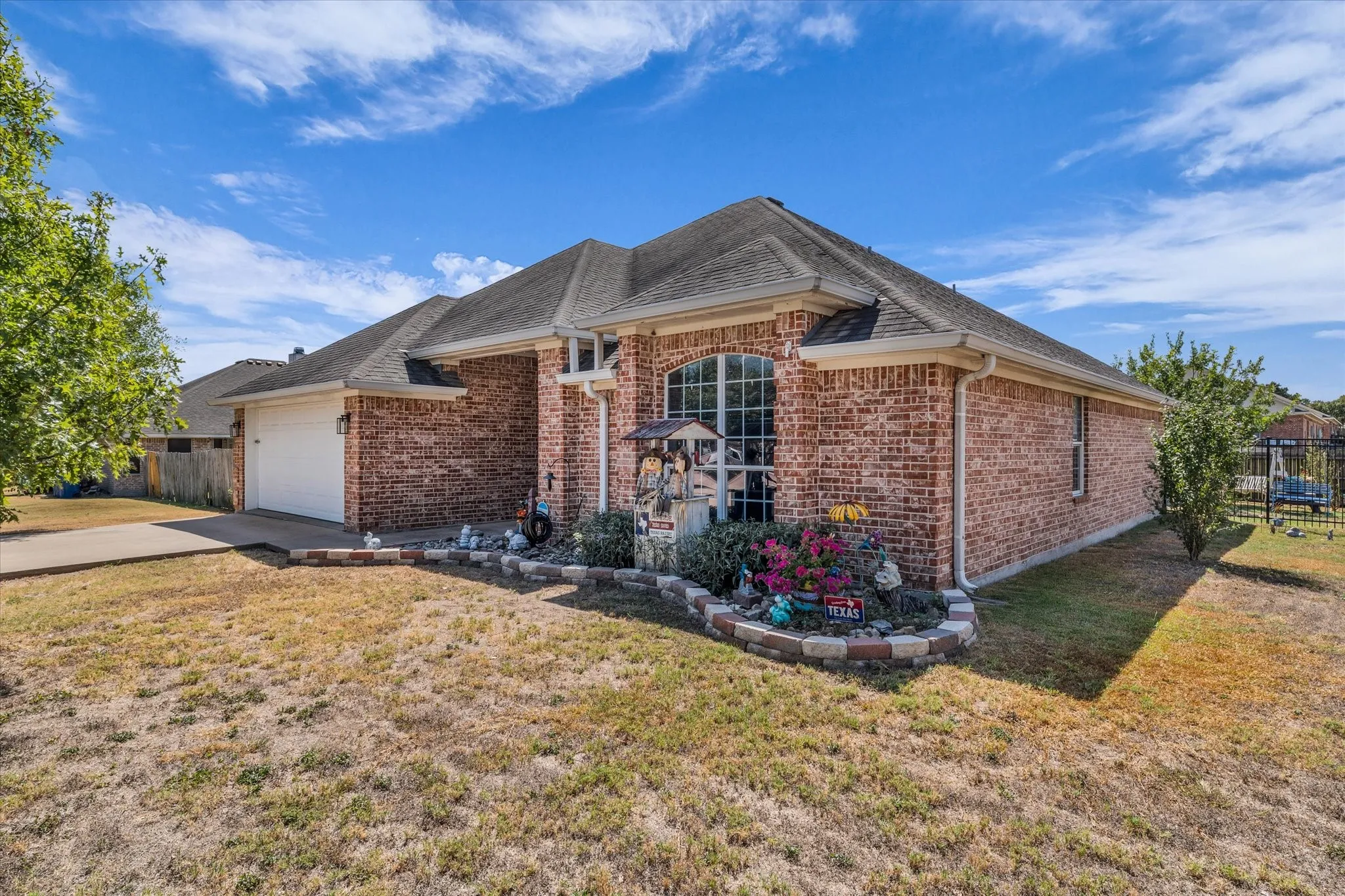 Brick exterior with an arched window, attached garage, and a stone-edged flower bed