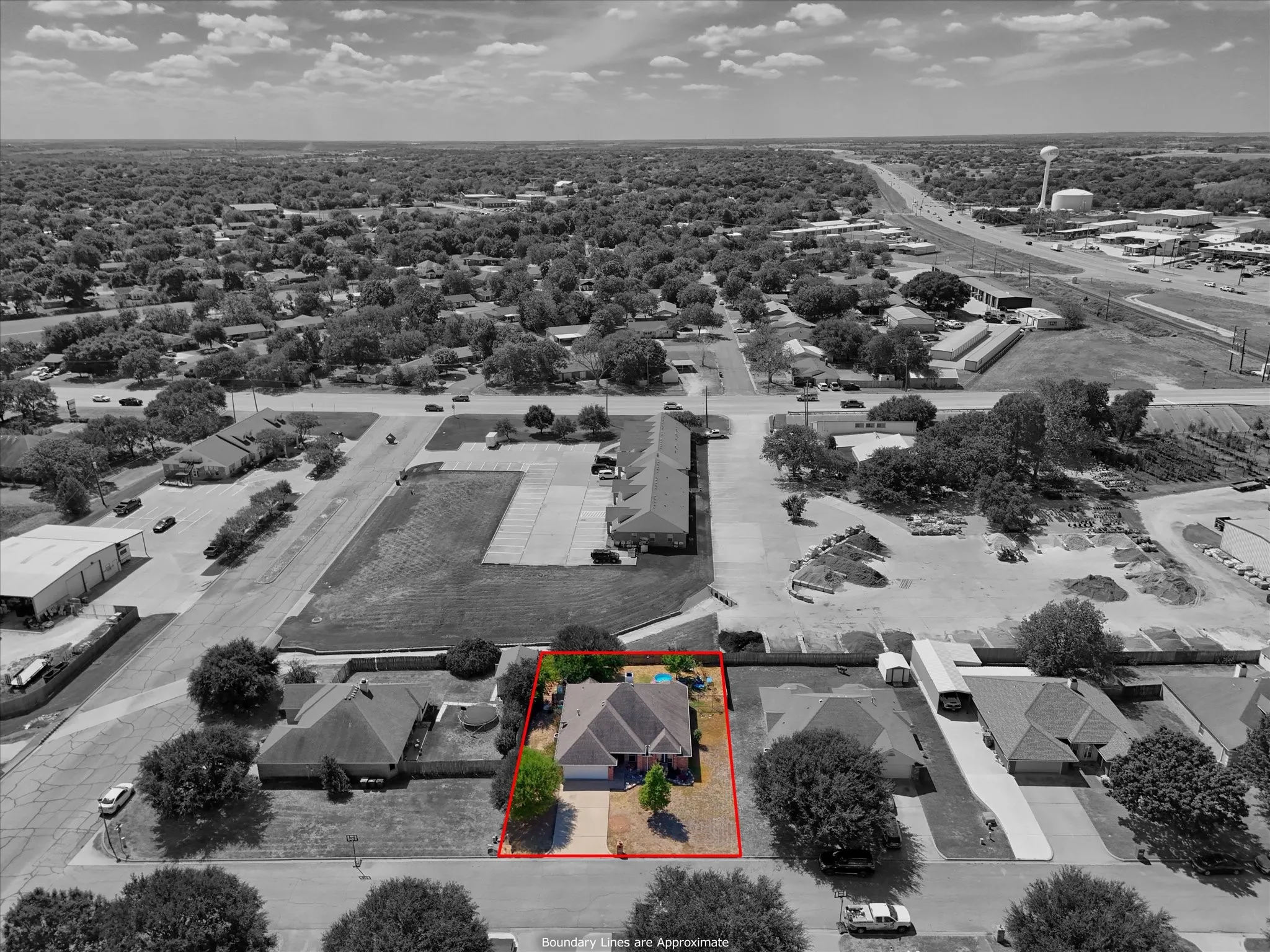 Single-story residence with an attached garage, a paved driveway, and a fenced backyard featuring a pool