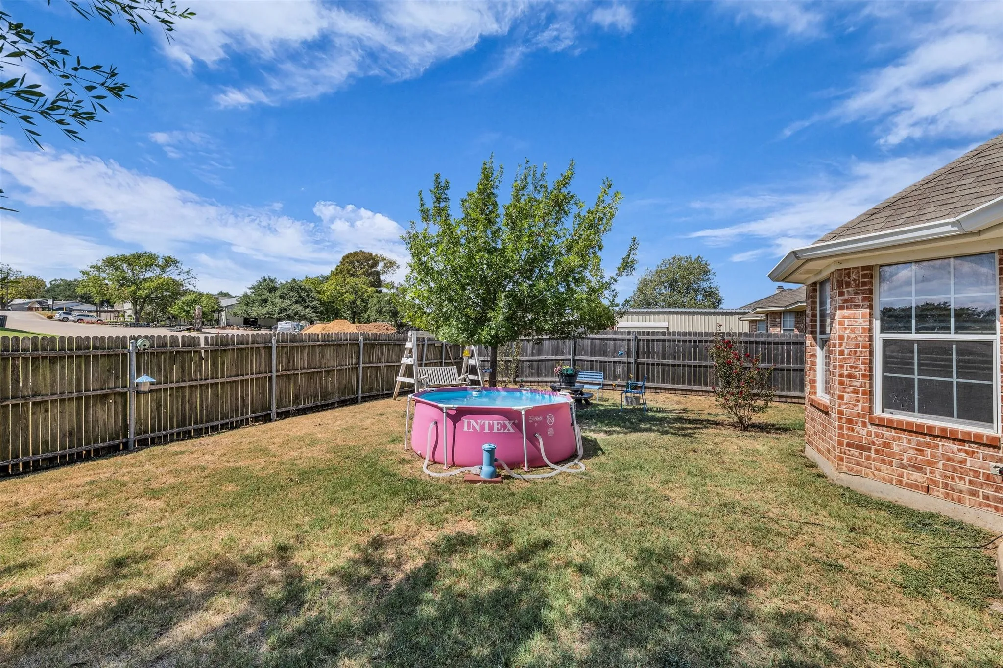 Private backyard with wood privacy fencing, mature tree, and brick exterior