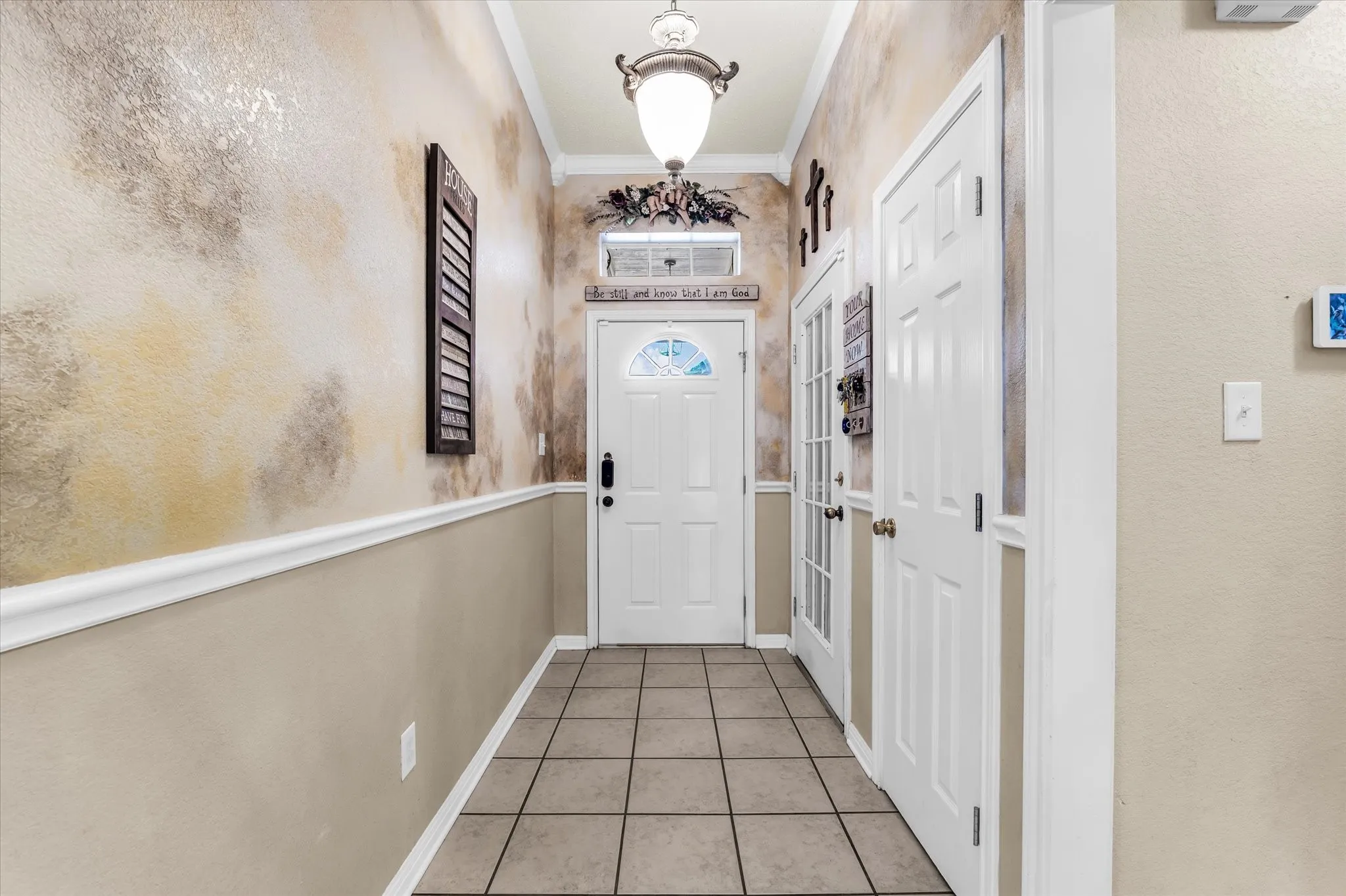 Tiled flooring, wainscoting with decorative molding, and a built-in ceiling light fixture