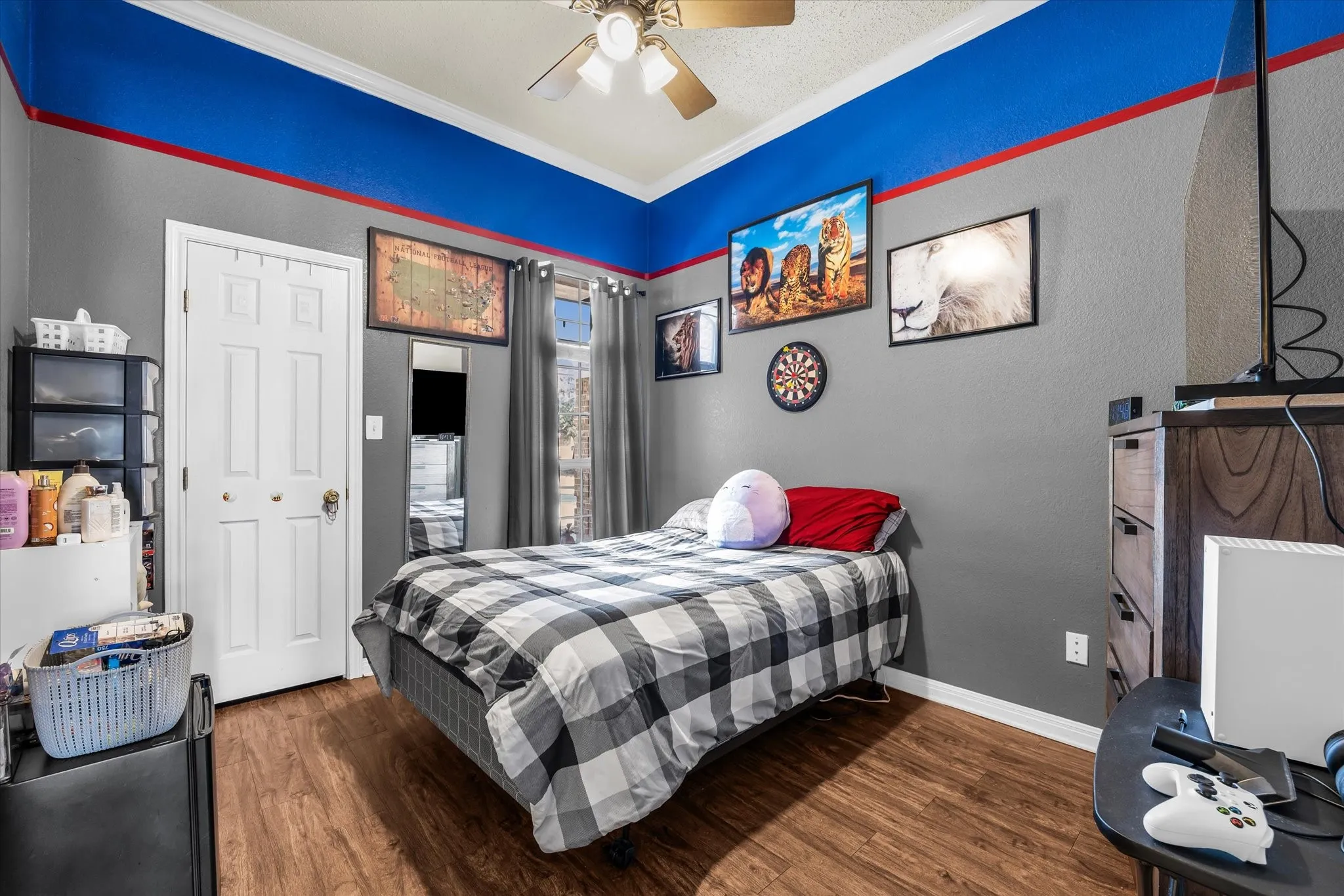 Wood-finish flooring, ceiling fan with integrated lighting, window with drapes, and a paneled door