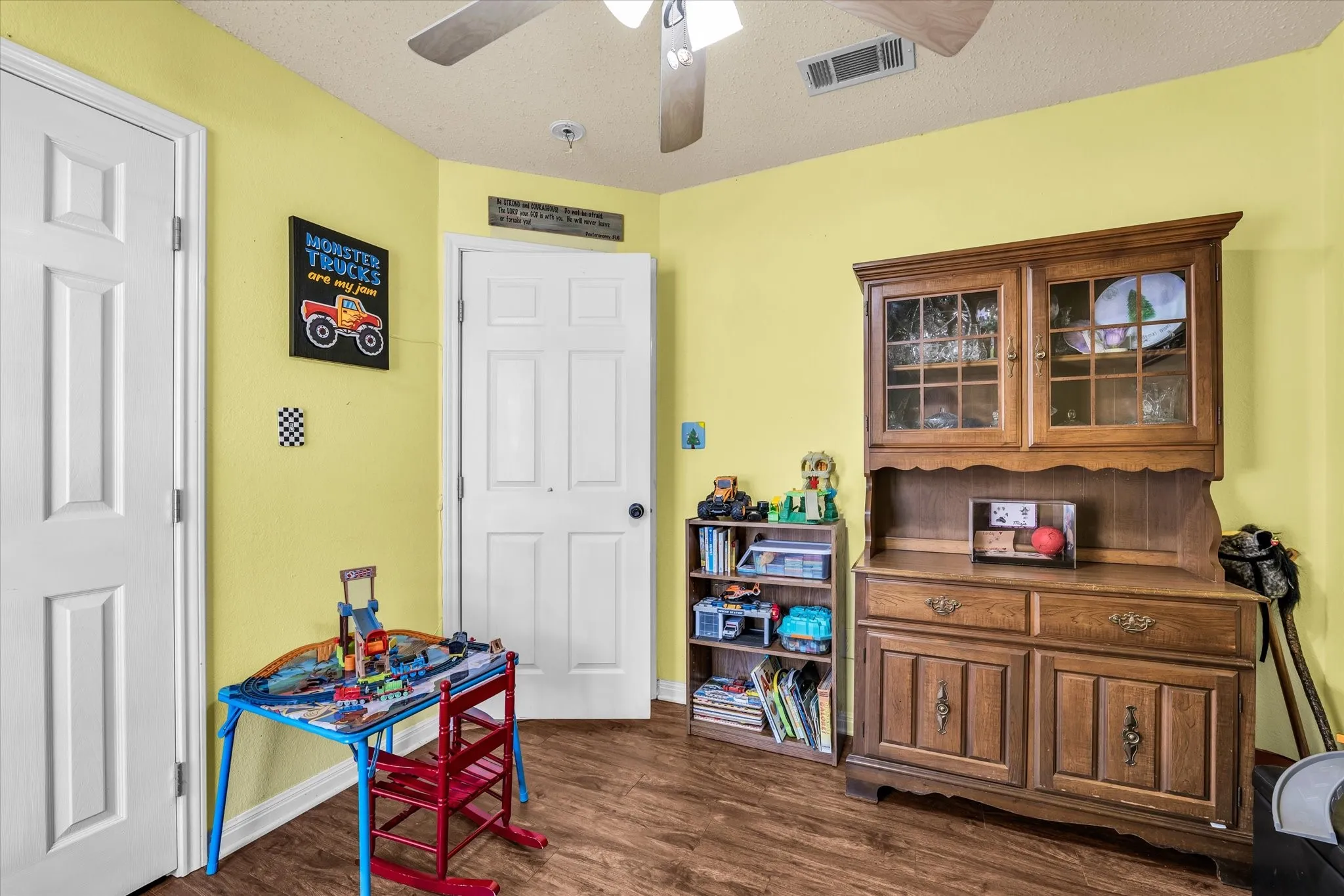 Wood-finish flooring with two white panel doors and a built-in ceiling fan