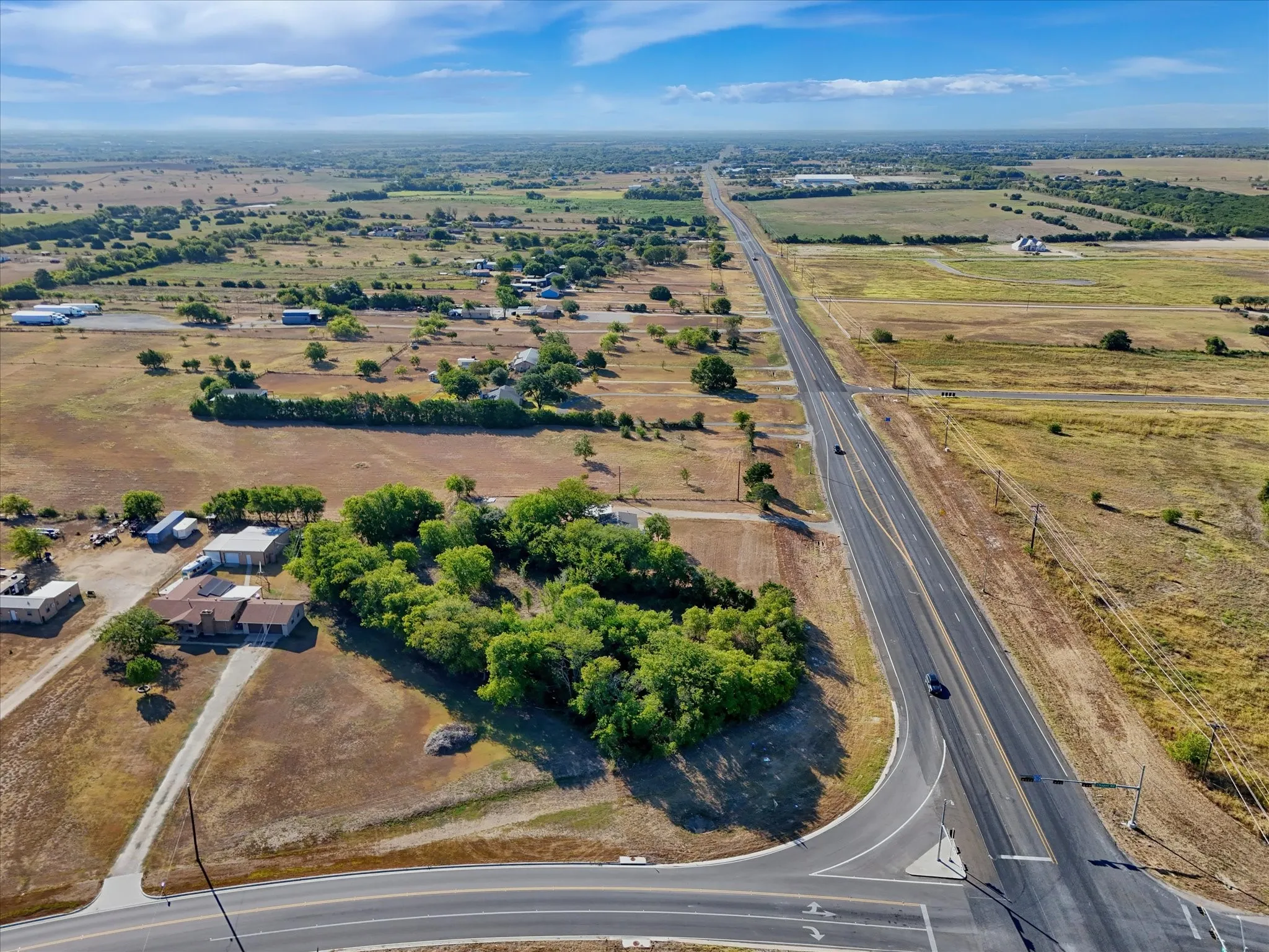 Expansive rural property featuring a single-story residence, multiple outbuildings, and a tree-lined perimeter