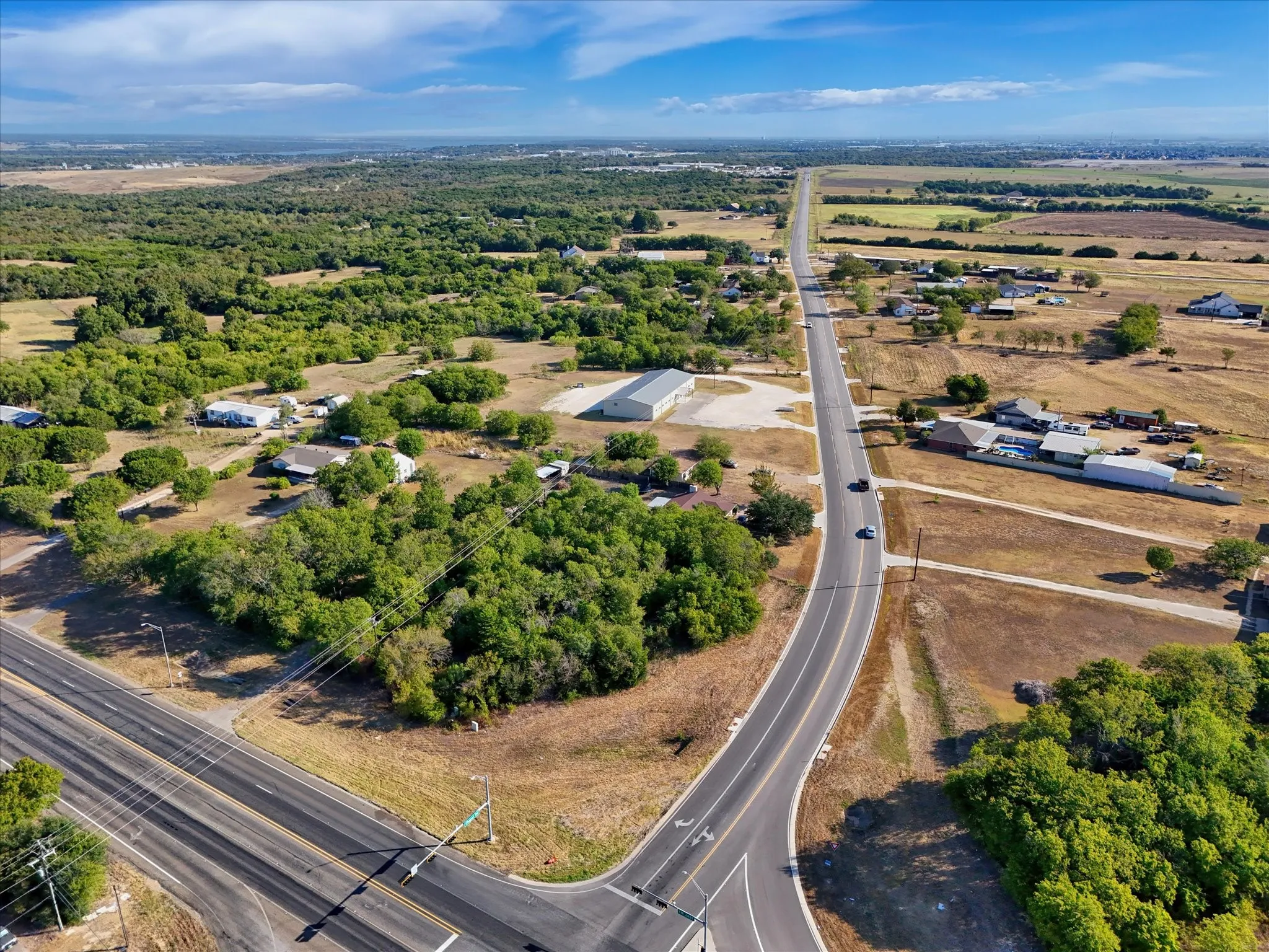 Expansive undeveloped land featuring mature trees and clearings with direct road frontage