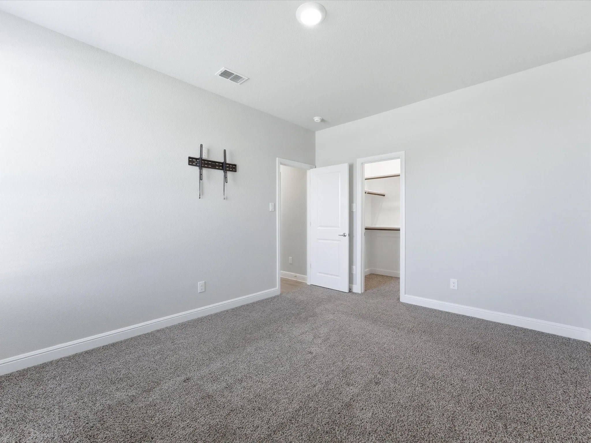 Carpeted flooring, recessed lighting, white interior doors, and a built-in wall mount