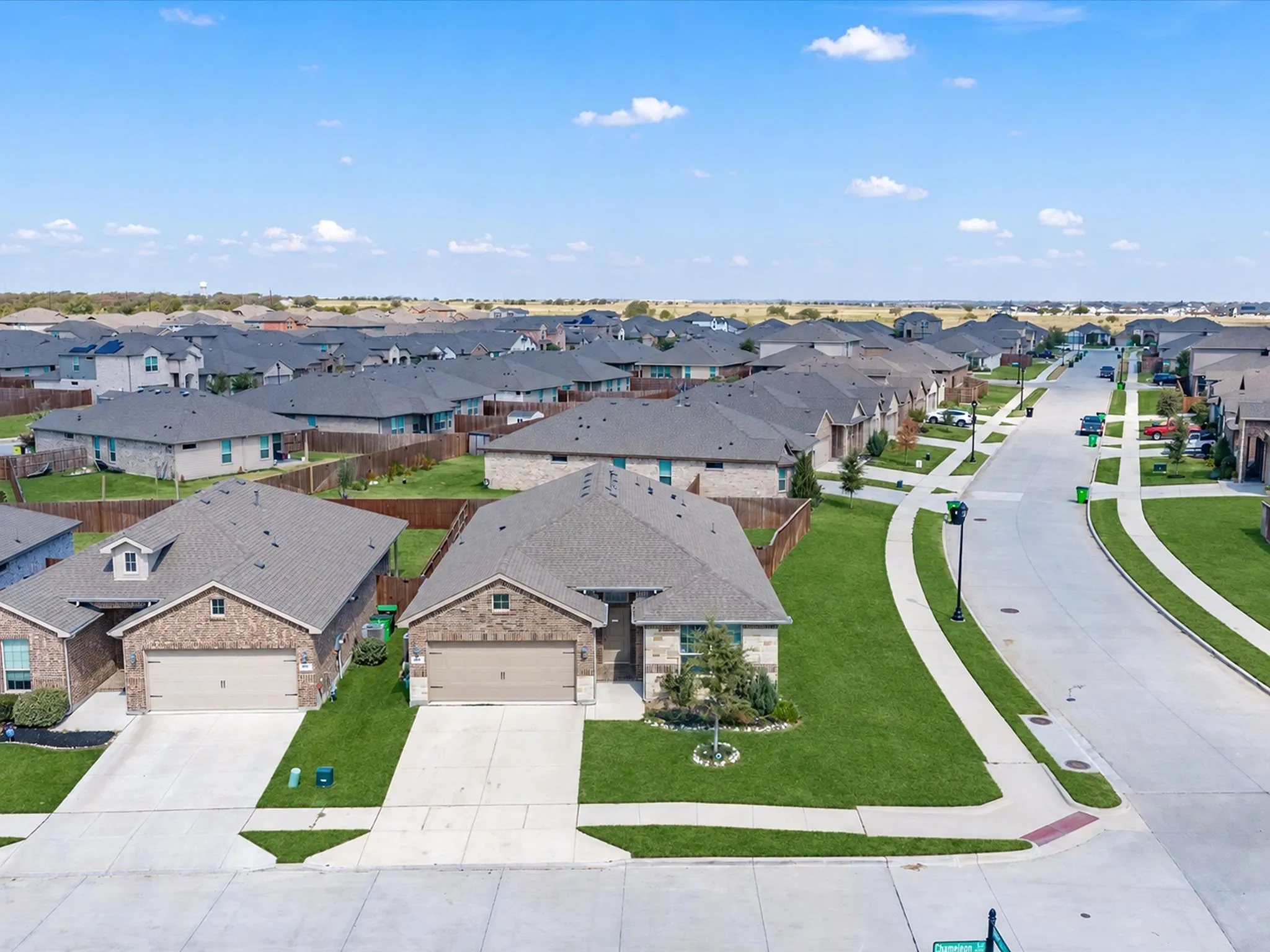 Residential neighborhood featuring single-story homes with brick exteriors, asphalt shingle roofs, attached garages, and concrete driveways