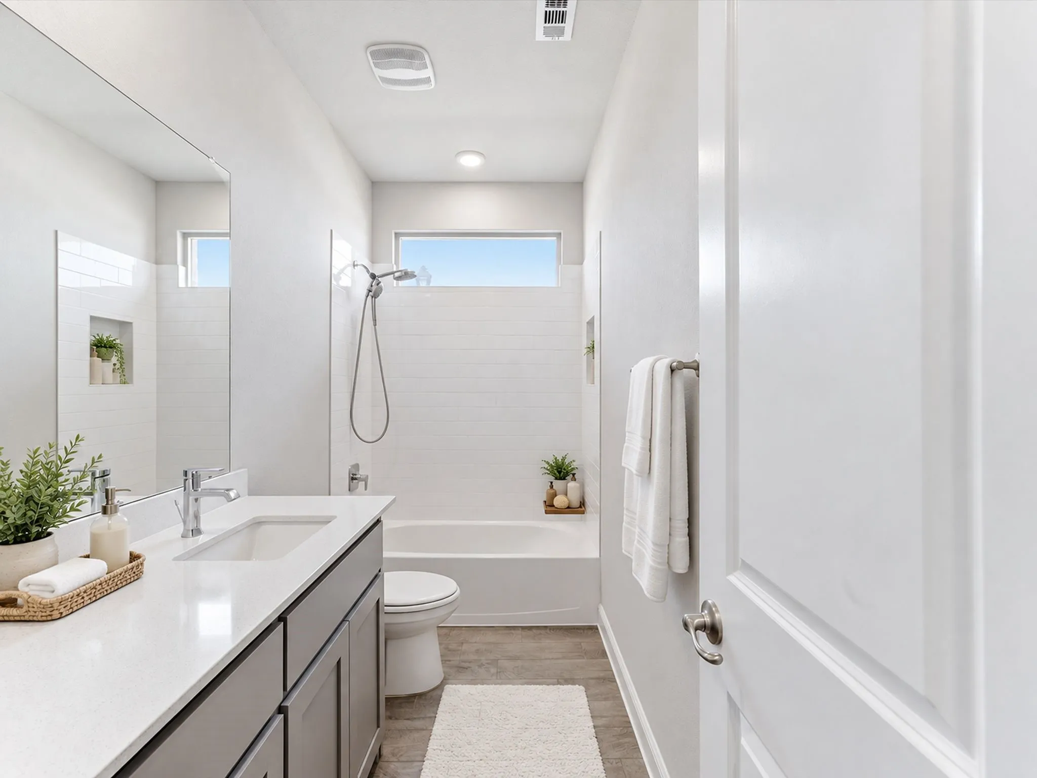 Vanity with a white countertop and undermount sink, wood-finish flooring, white subway tile shower surround, and built-in shower niche