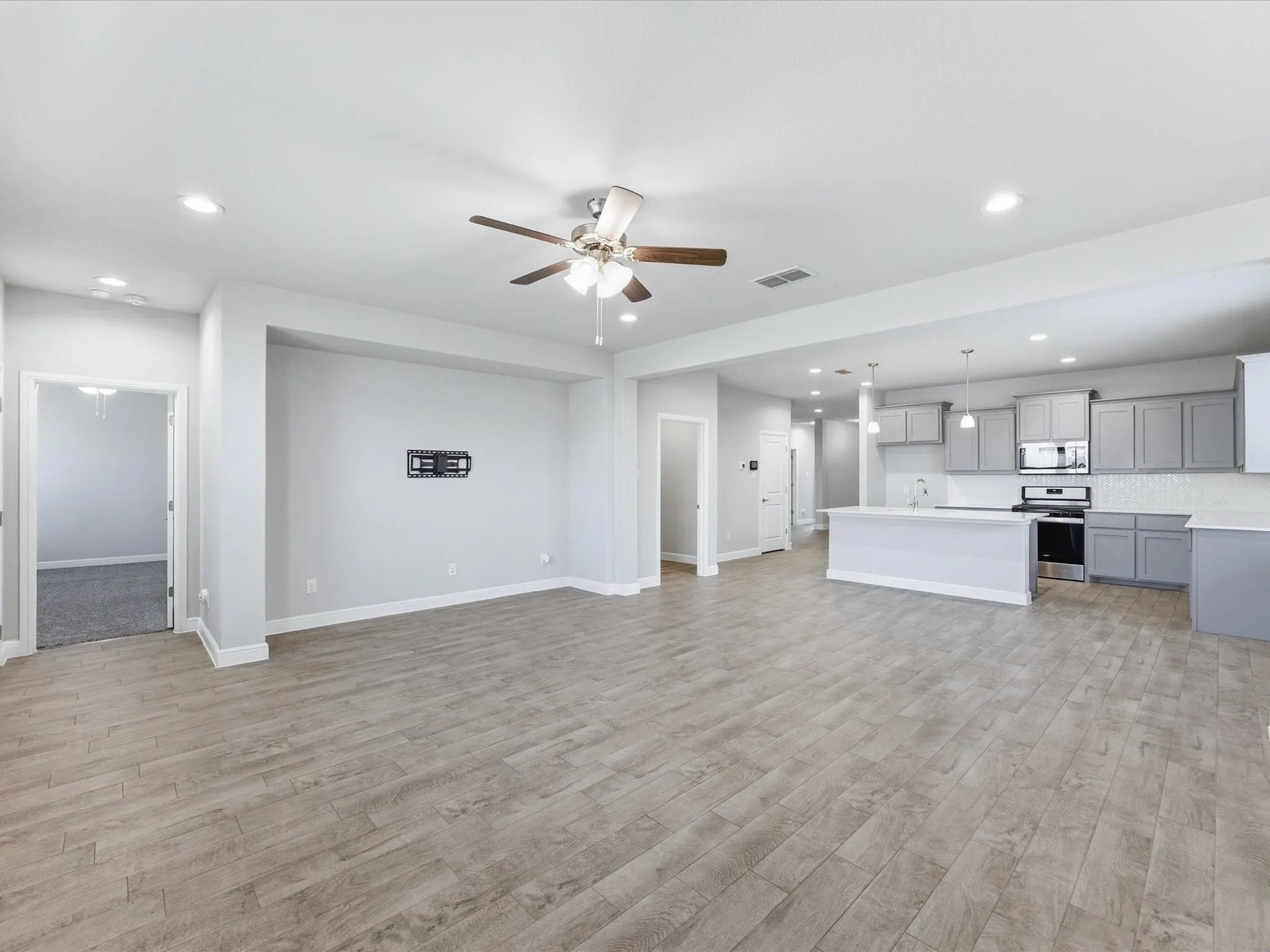 Open-concept living space with wood-finish flooring, recessed lighting, and a ceiling fan