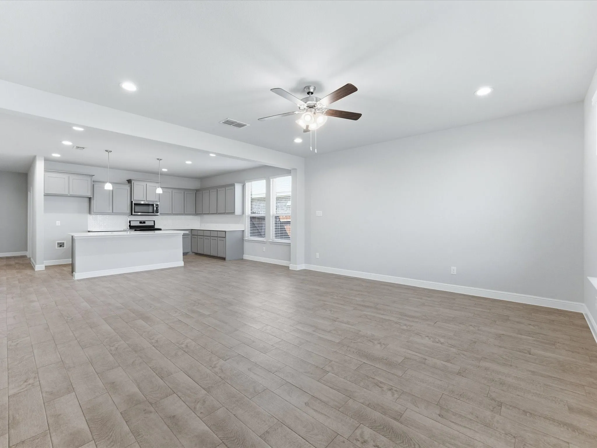 Open concept living area with wood-finish flooring, recessed lighting, and a ceiling fan