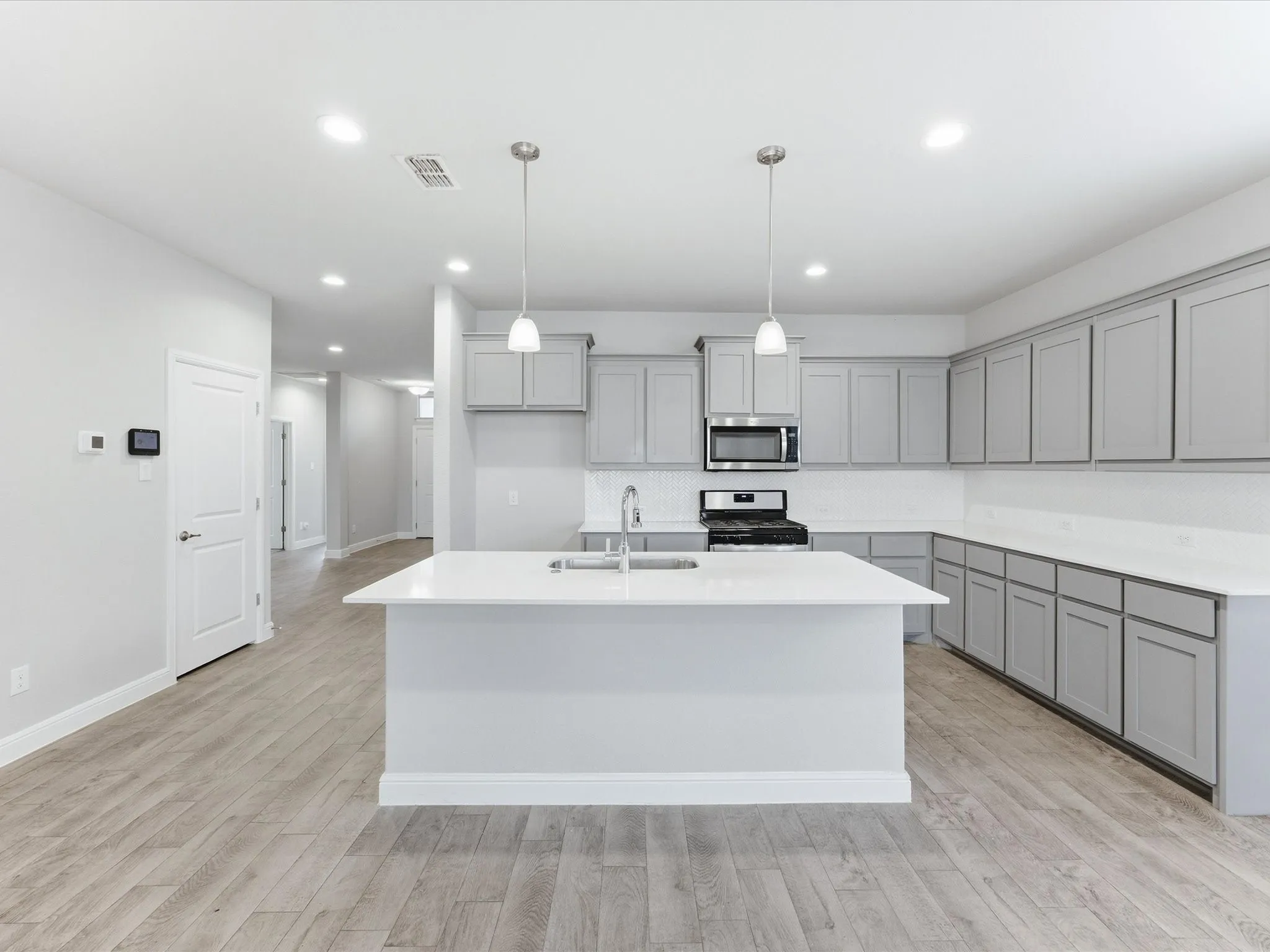 Kitchen featuring an expansive island, light gray cabinetry, white countertops, wood-finish flooring, and recessed lighting