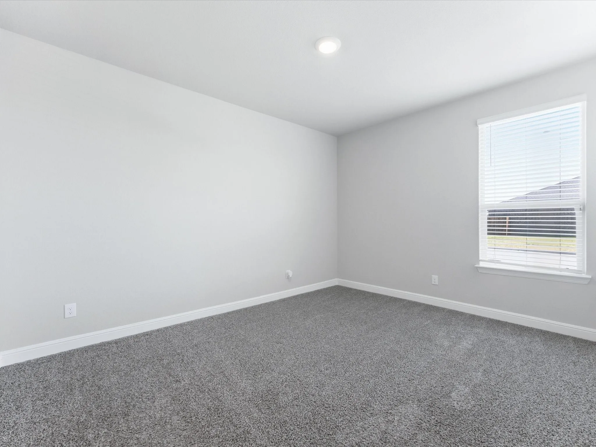 Recessed ceiling lighting, a single window with blinds, light gray wall finishes, and gray carpeting