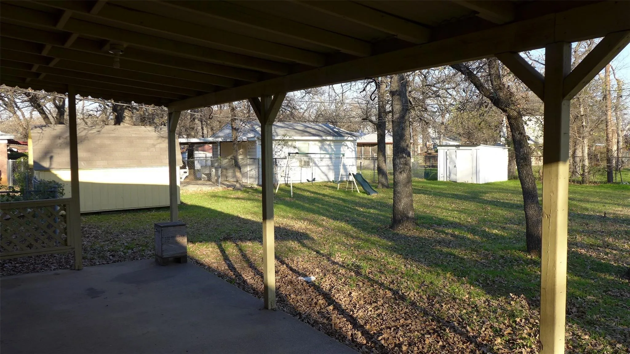 Covered patio with a concrete surface, expansive lawn, and mature trees