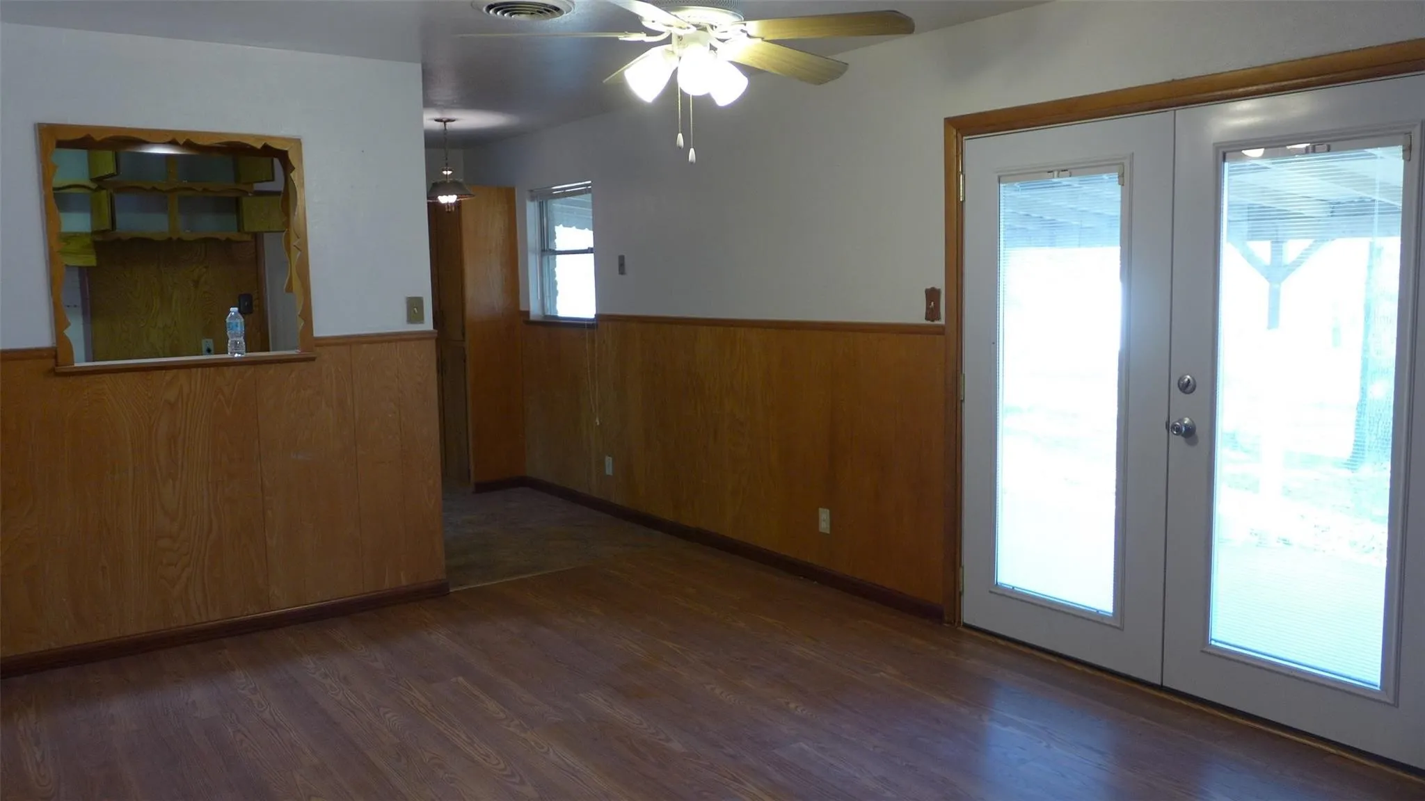 Wood-finish flooring, wood paneling, ceiling fan, and double exterior doors
