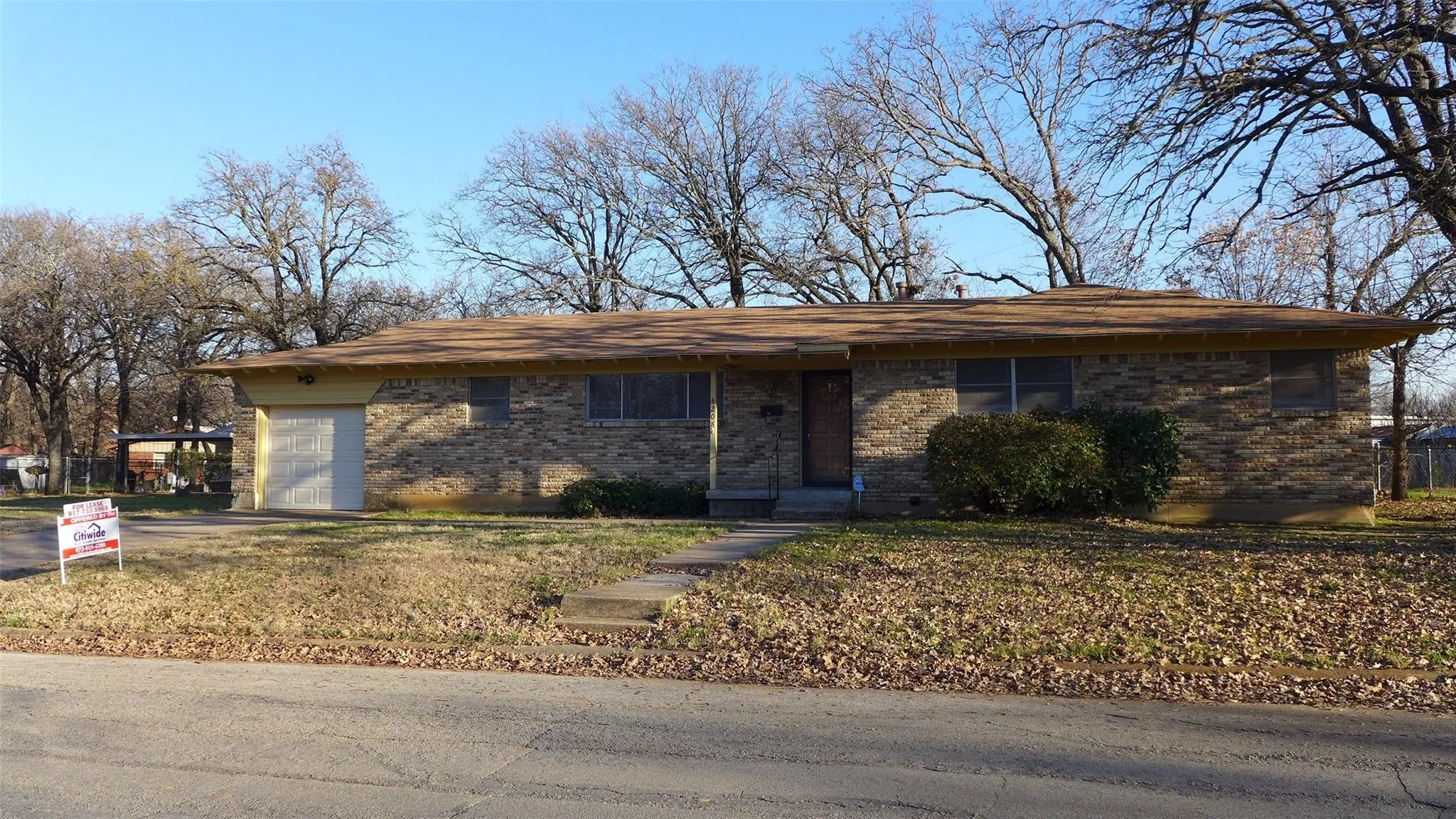 Brick exterior with an attached garage, a concrete driveway, and a front walkway