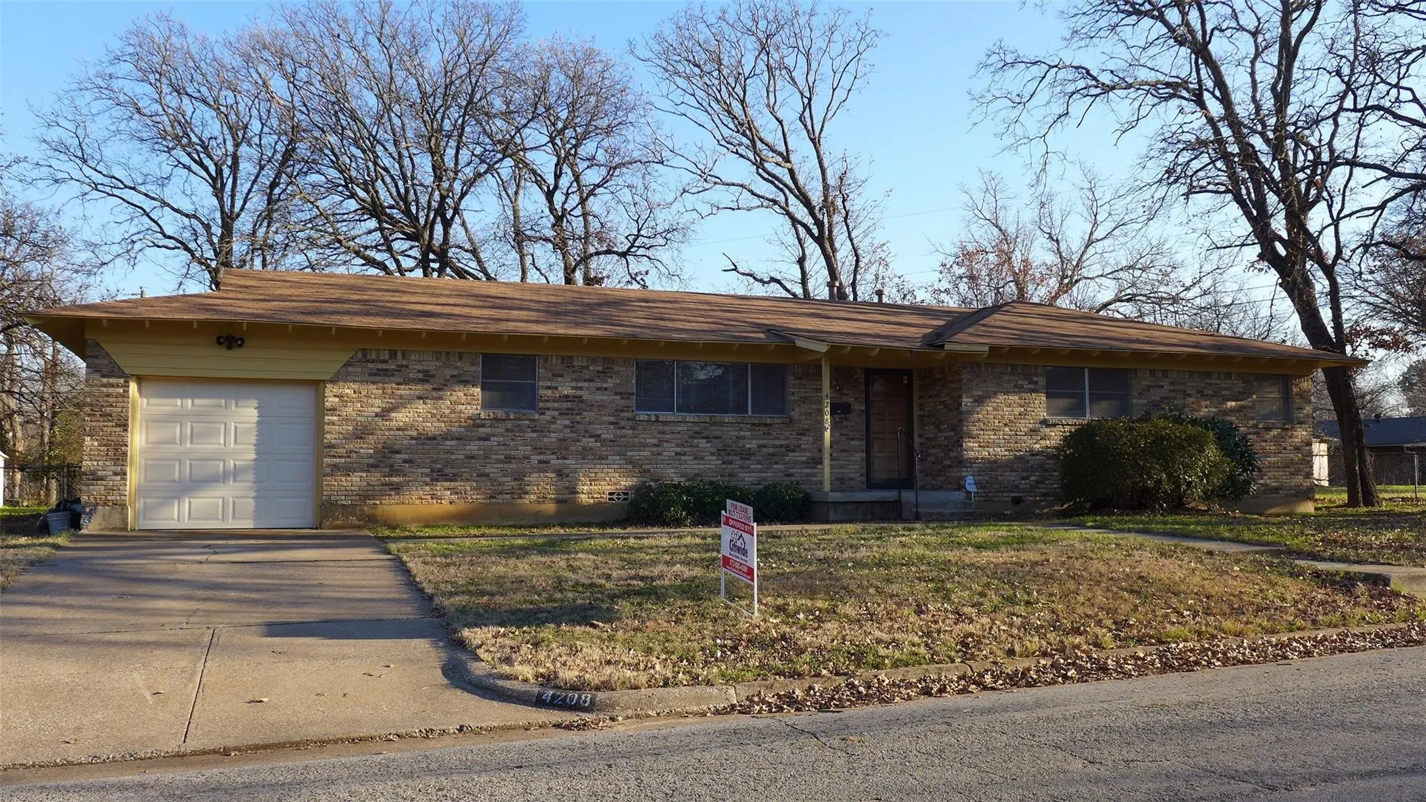 Brick exterior, attached garage, sloped roofline, established front yard, concrete driveway