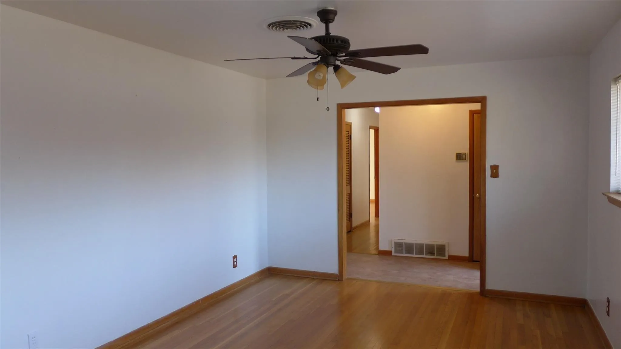 Hardwood flooring, painted walls, ceiling fan with integrated lighting, wood trim, and a window with blinds
