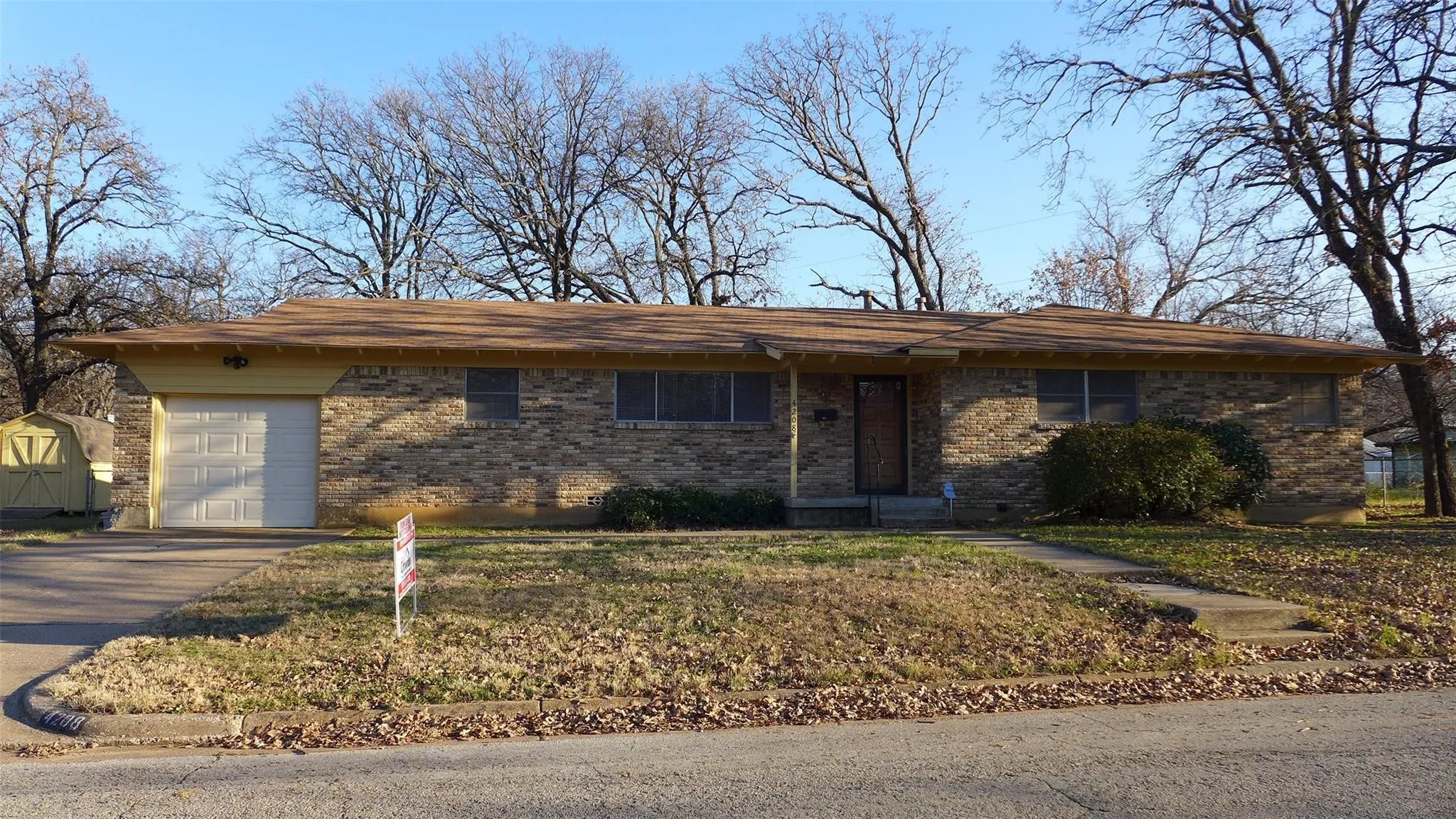 Brick exterior with attached garage, concrete driveway, and front walkway