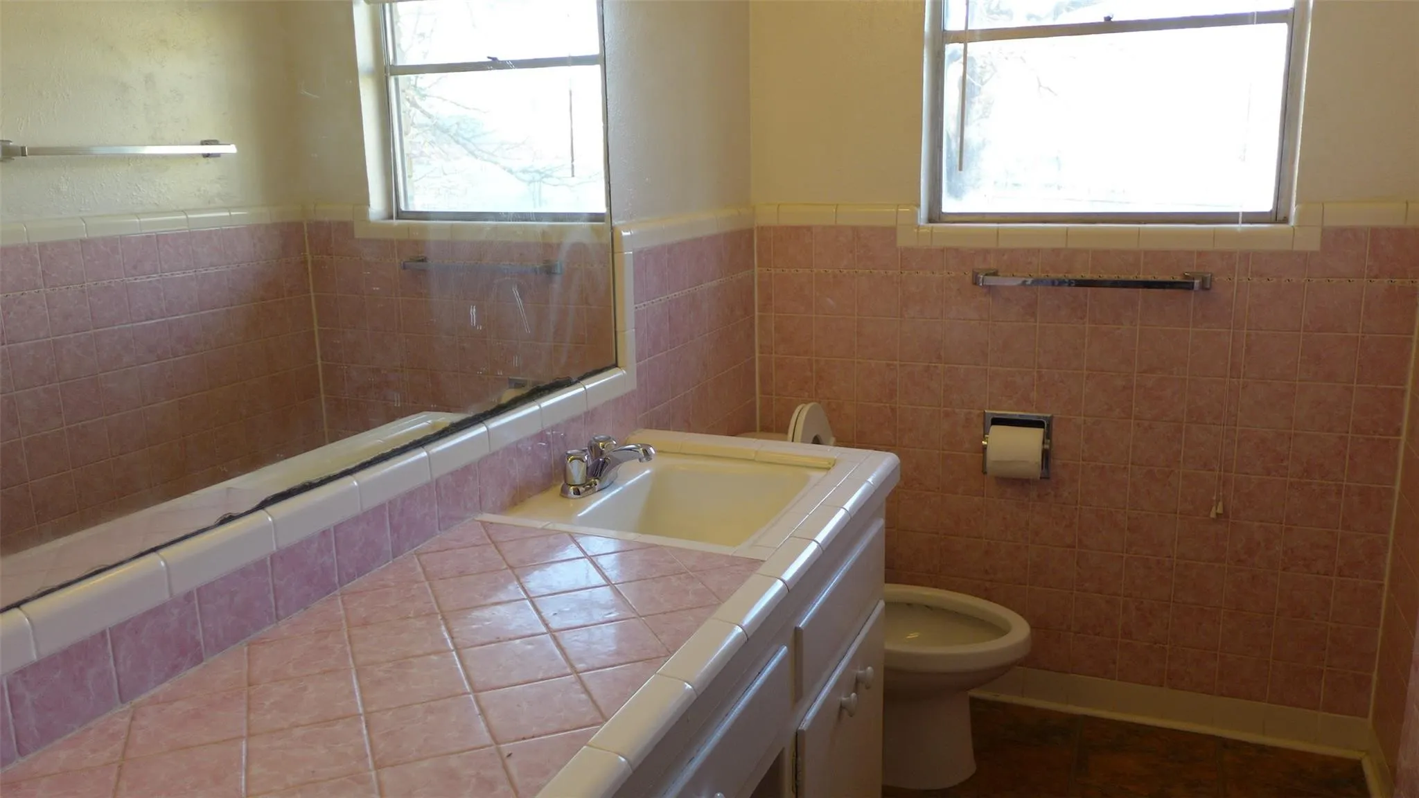 Bathroom featuring tiled walls, a vanity with an integrated sink, and an elongated mirror
