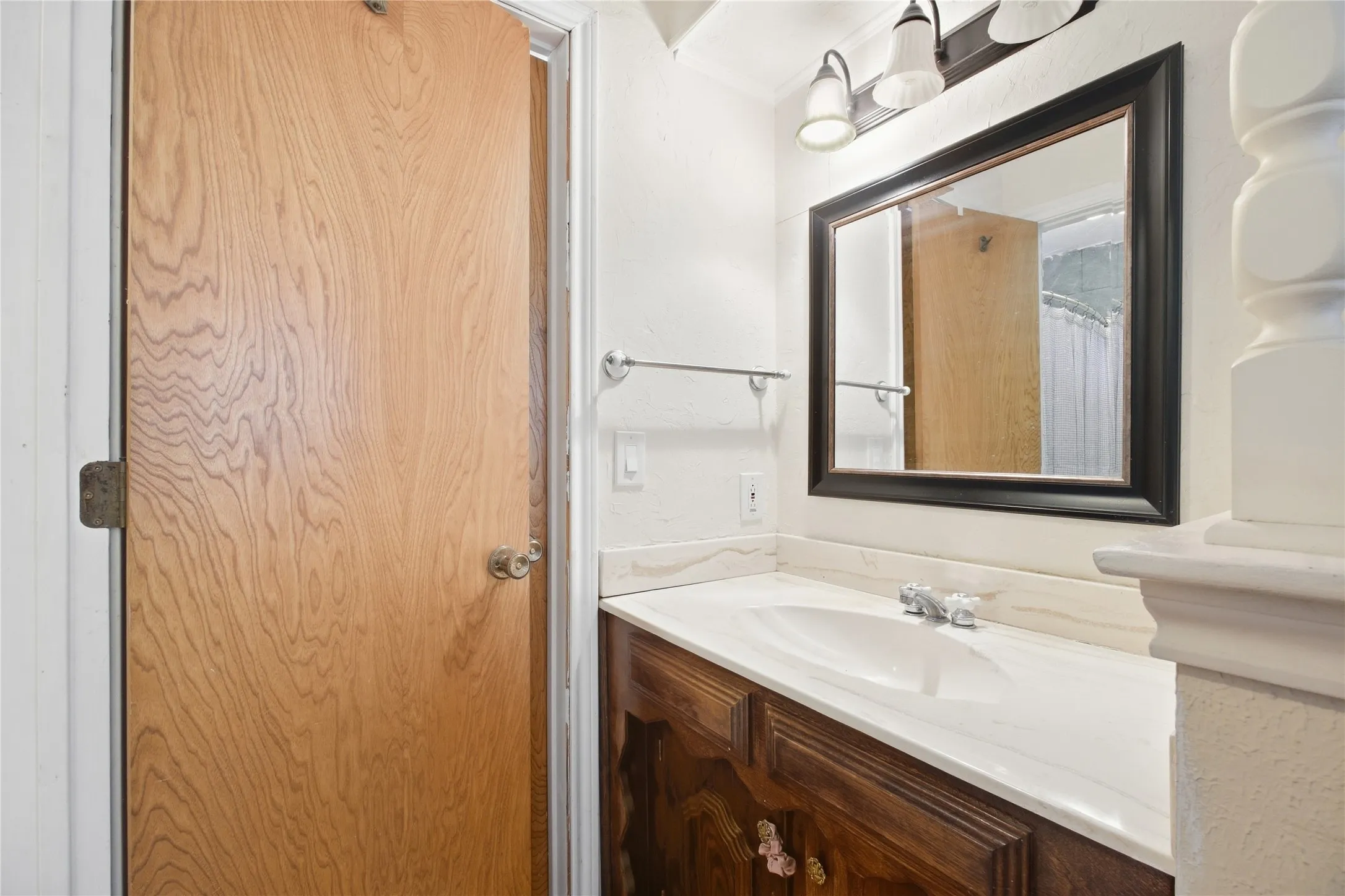 Wood-finish vanity with an integrated sink and chrome faucet