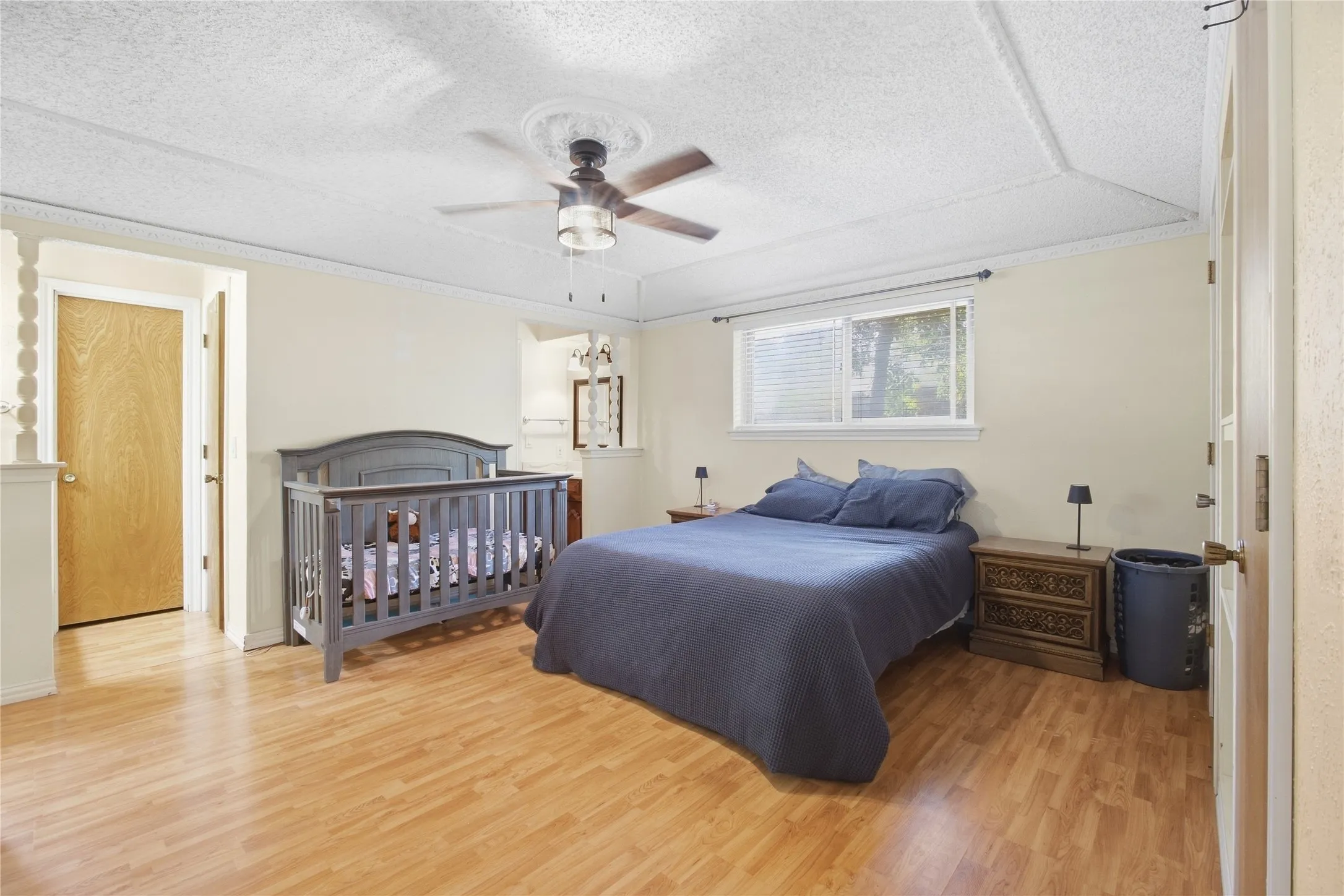 Wood-finish flooring throughout, complemented by a ceiling fan with light fixture, and a window with blinds