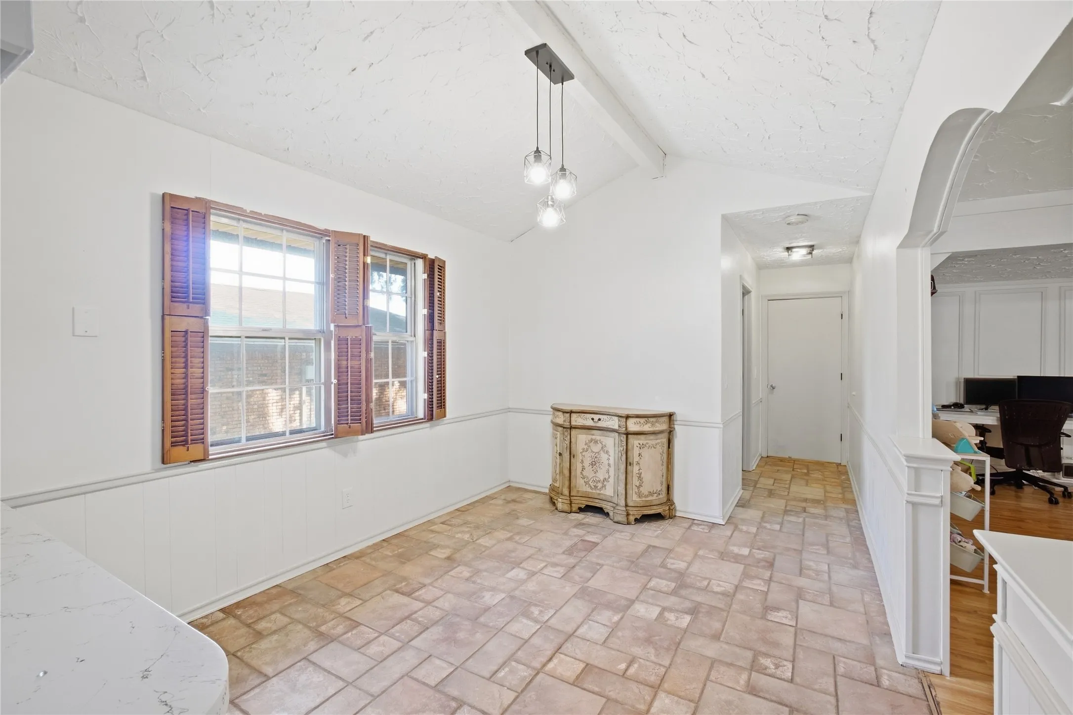 Vaulted ceiling, contemporary pendant lighting, window with operable shutters, wainscoting, tile flooring
