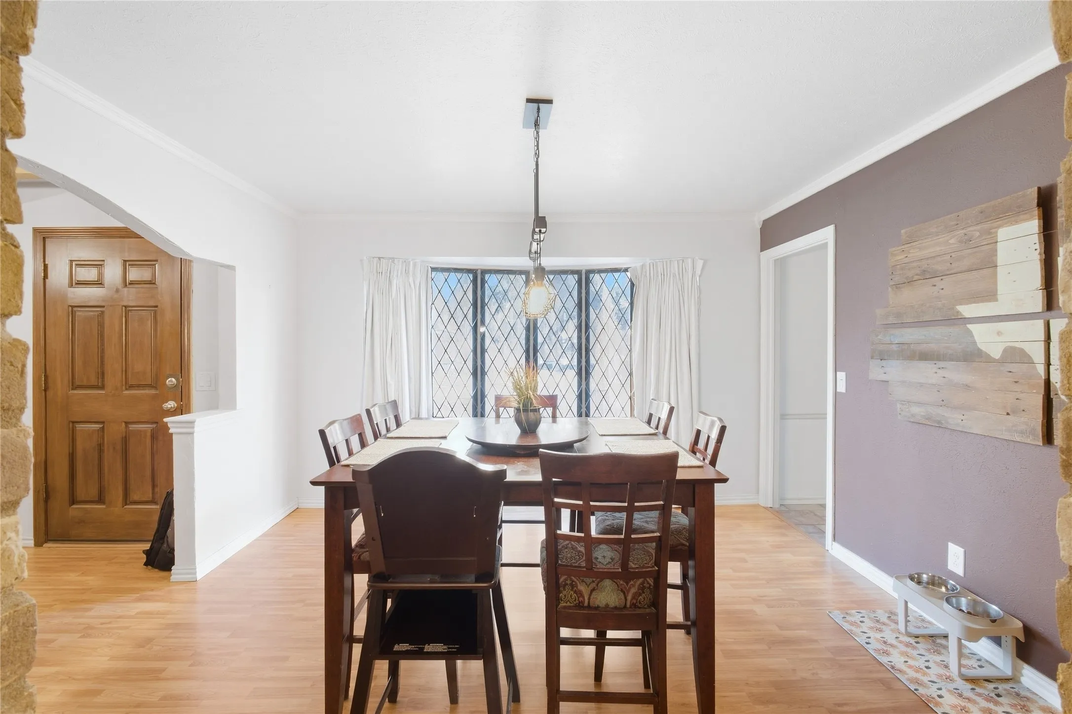 Wood-finish flooring, crown molding, and a decorative window