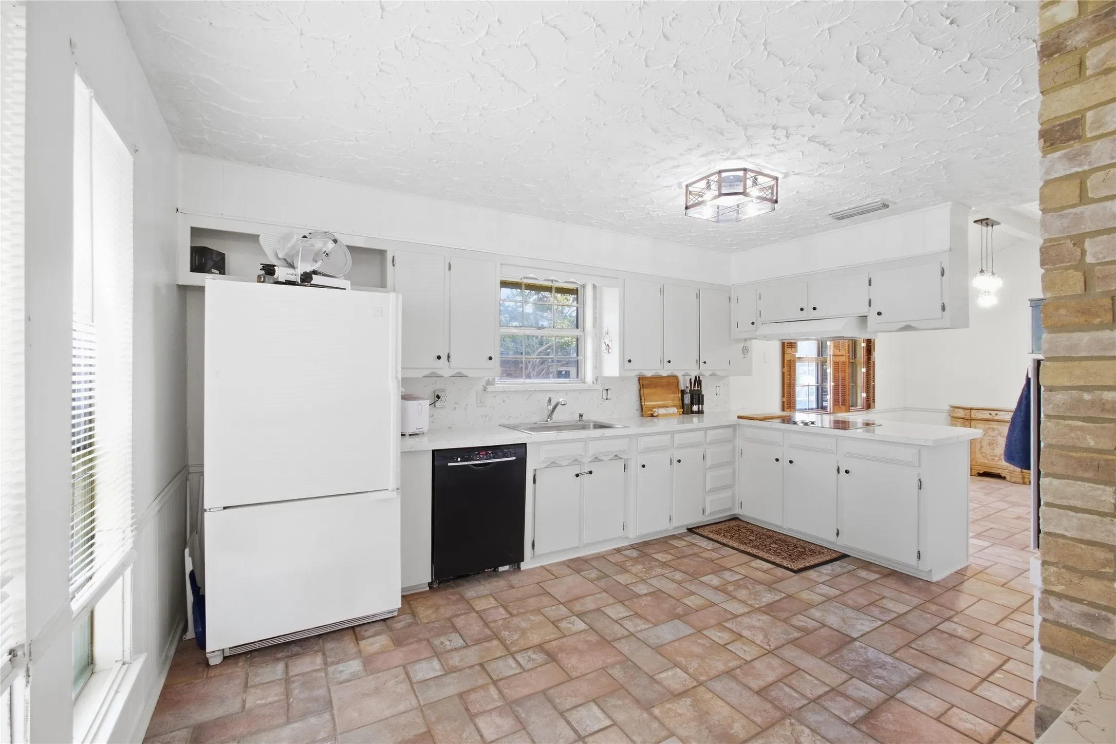 Kitchen featuring white cabinetry, a black dishwasher, a white refrigerator, a stainless steel sink, and tile flooring