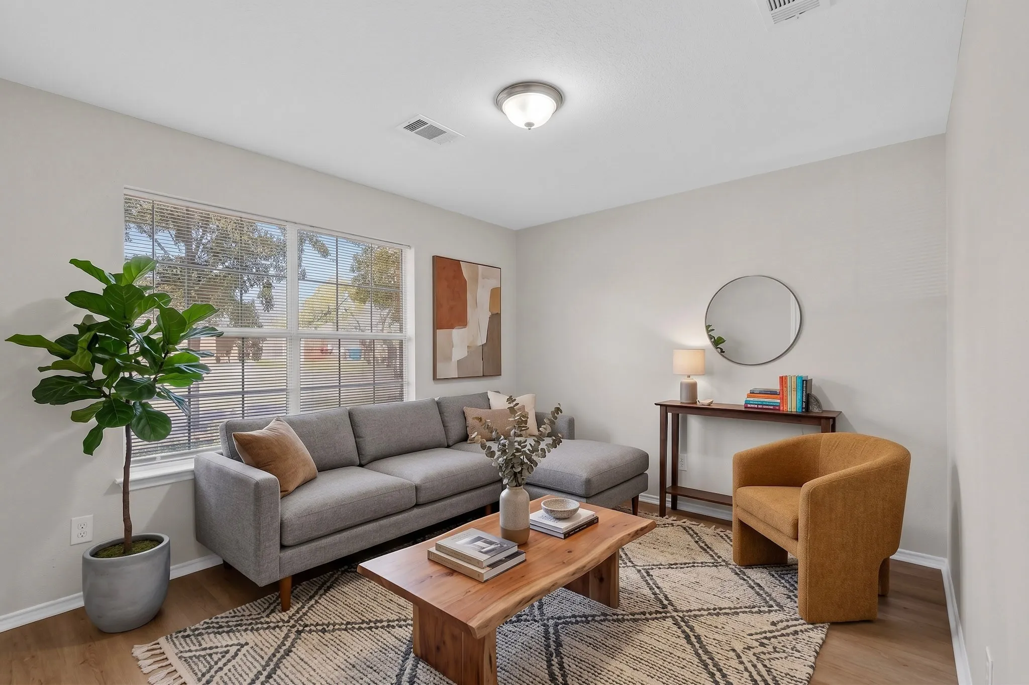 Bright living space featuring wood-finish flooring, a large window, a flush mount ceiling light, and neutral wall tones
