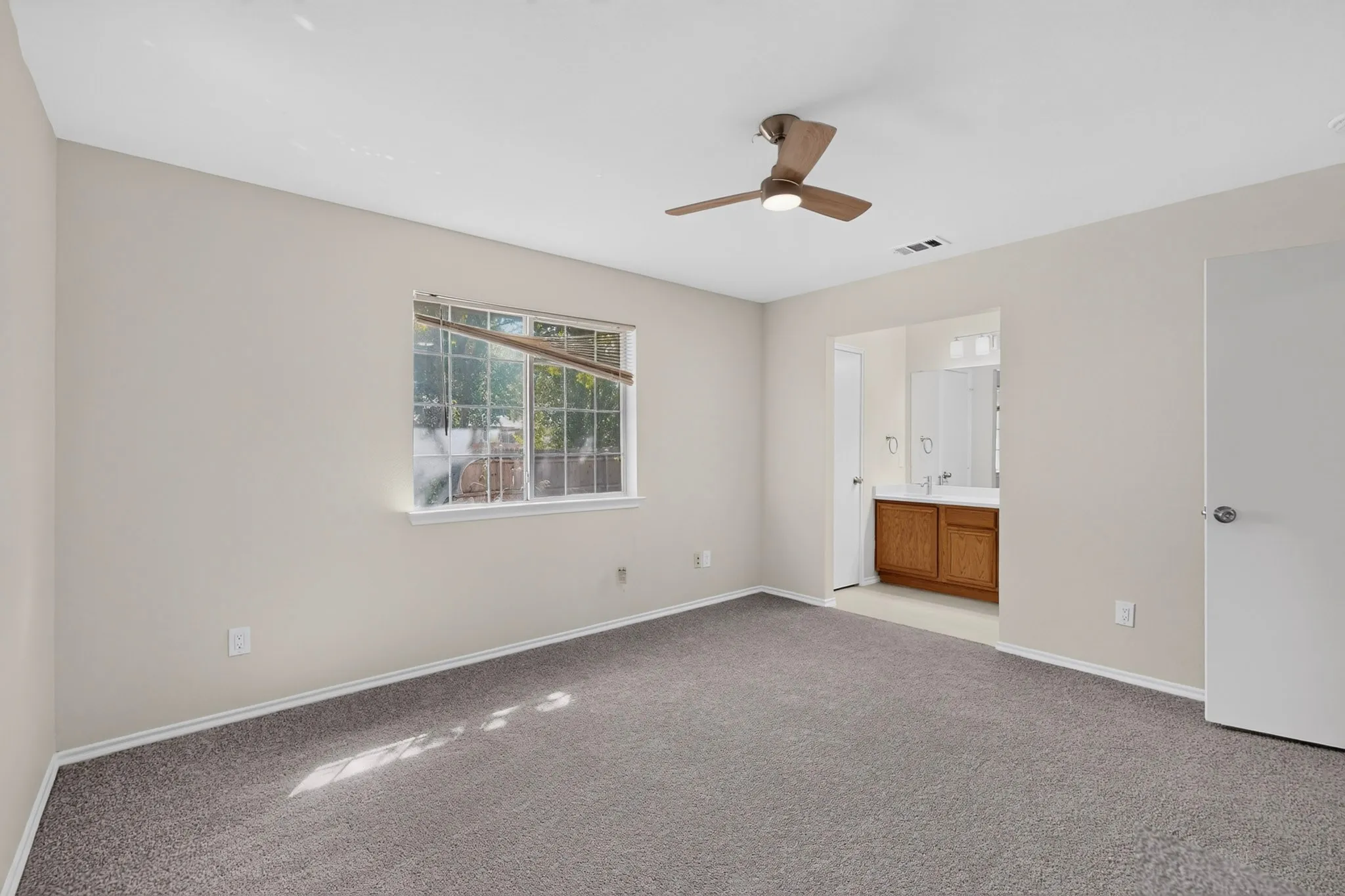 Spacious room with gray carpeting, an overhead ceiling fan, and a window