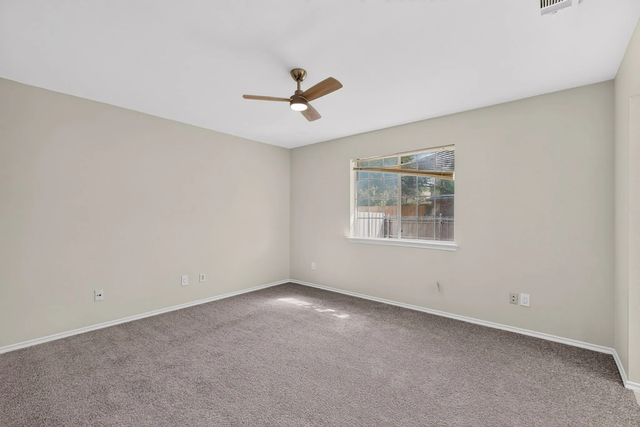 Neutral wall paint, ceiling fan with integrated lighting, window, and carpet flooring