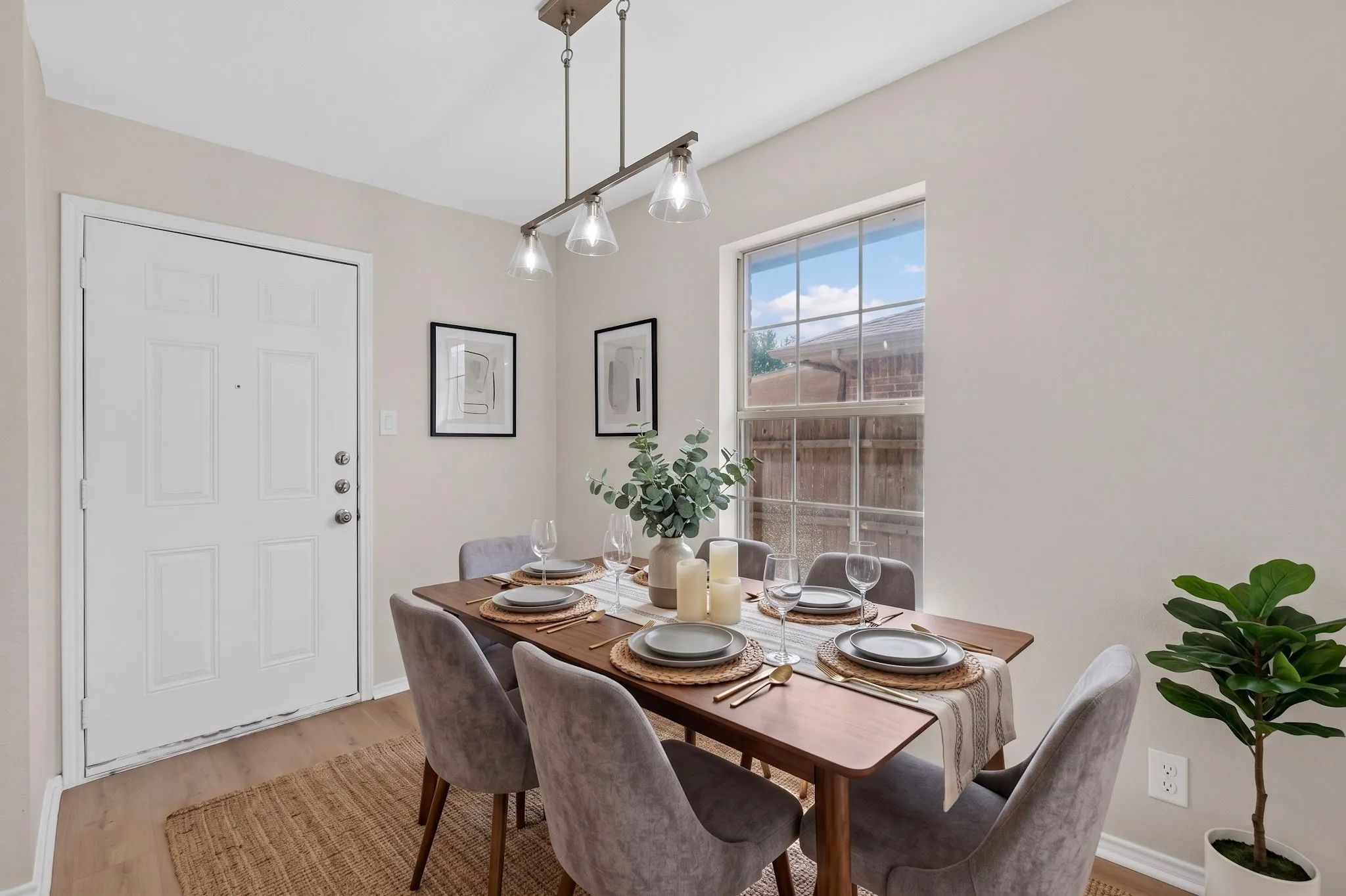 Wood-finish flooring, white paneled door, and a rectangular window with a privacy fence backdrop