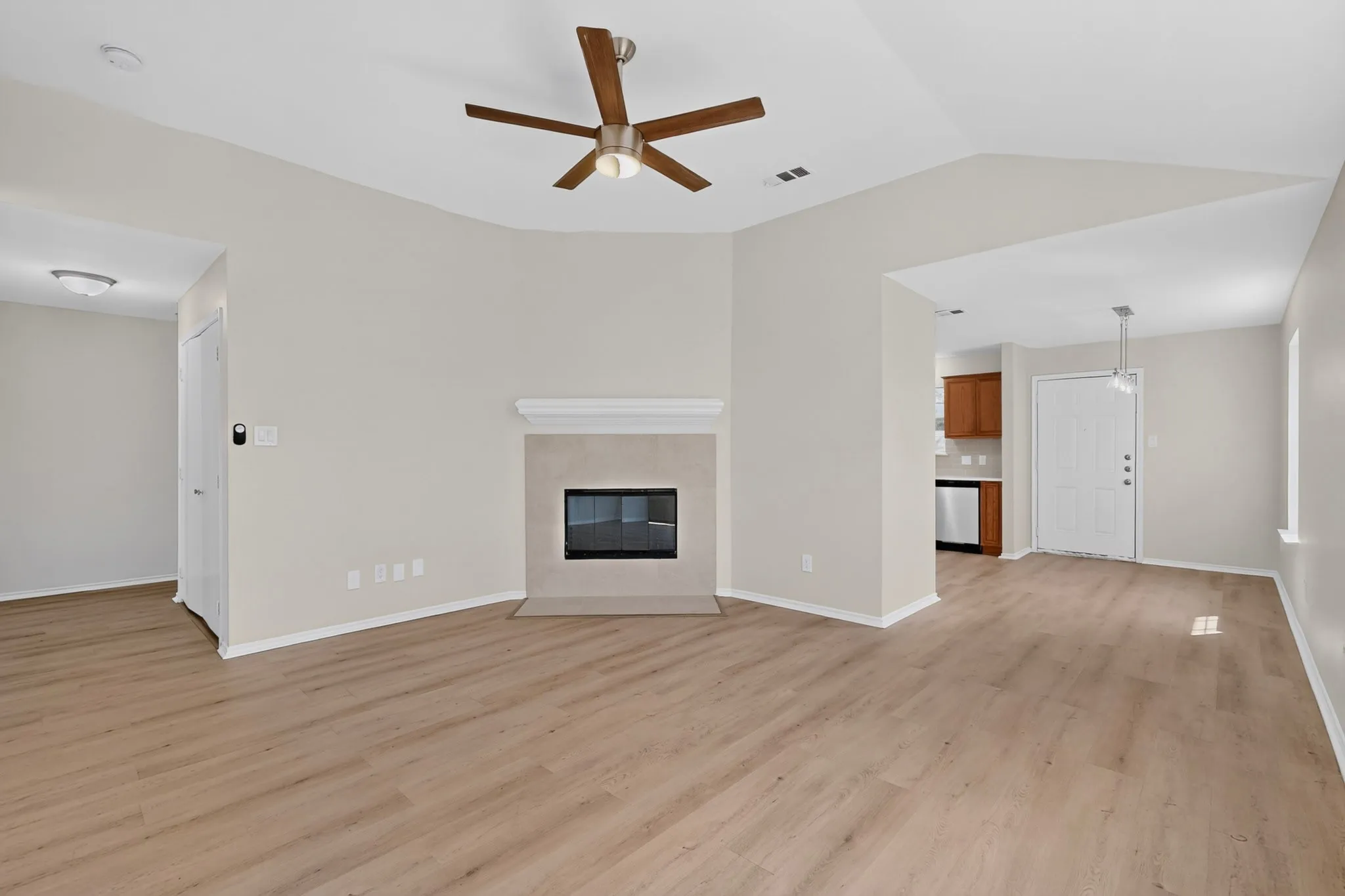 Vaulted ceiling with a ceiling fan, fireplace with a mantle, wood-finish flooring, and recessed lighting