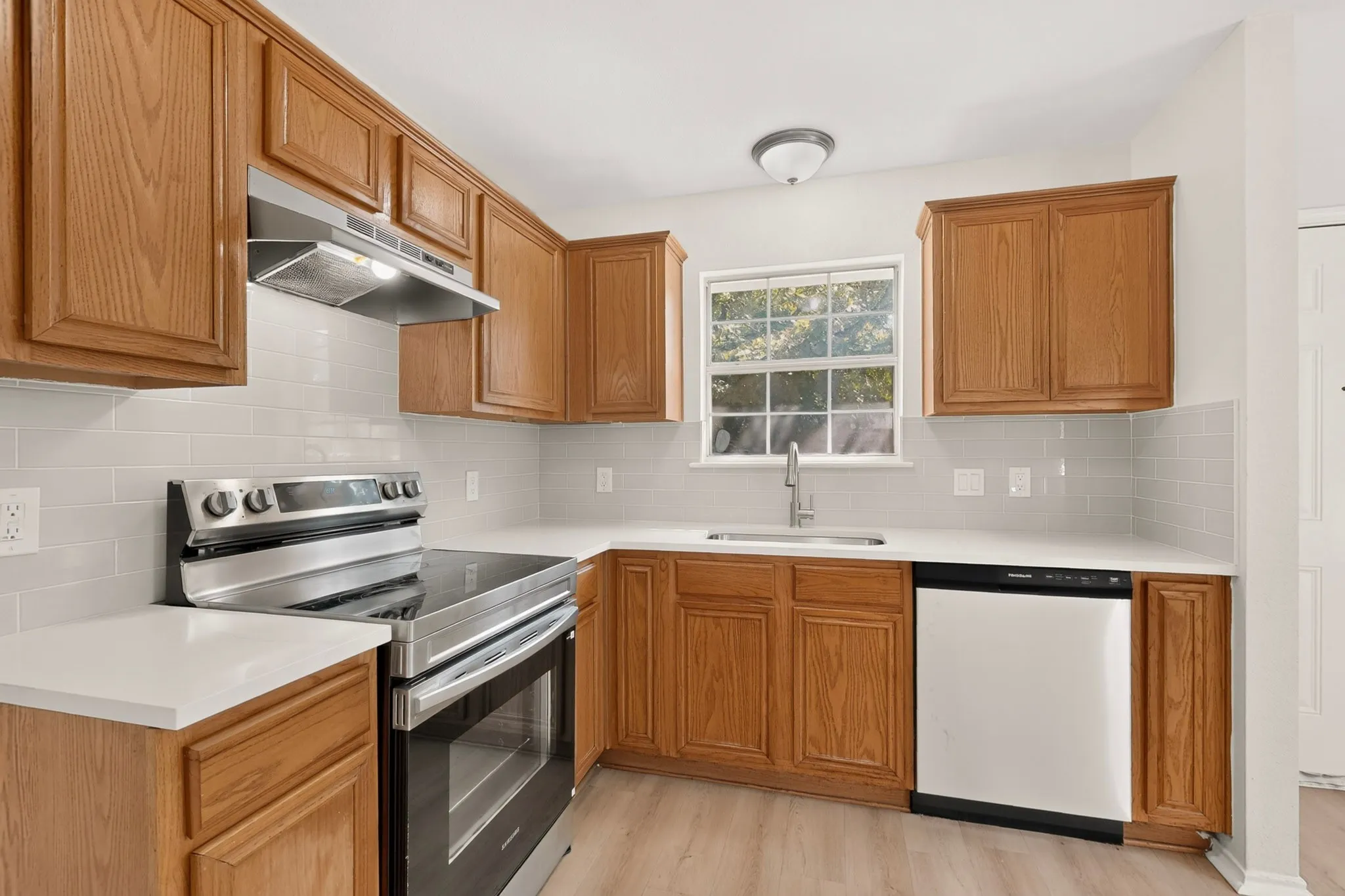 Kitchen featuring wood cabinetry, white countertops, stainless steel appliances, and a subway tile backsplash