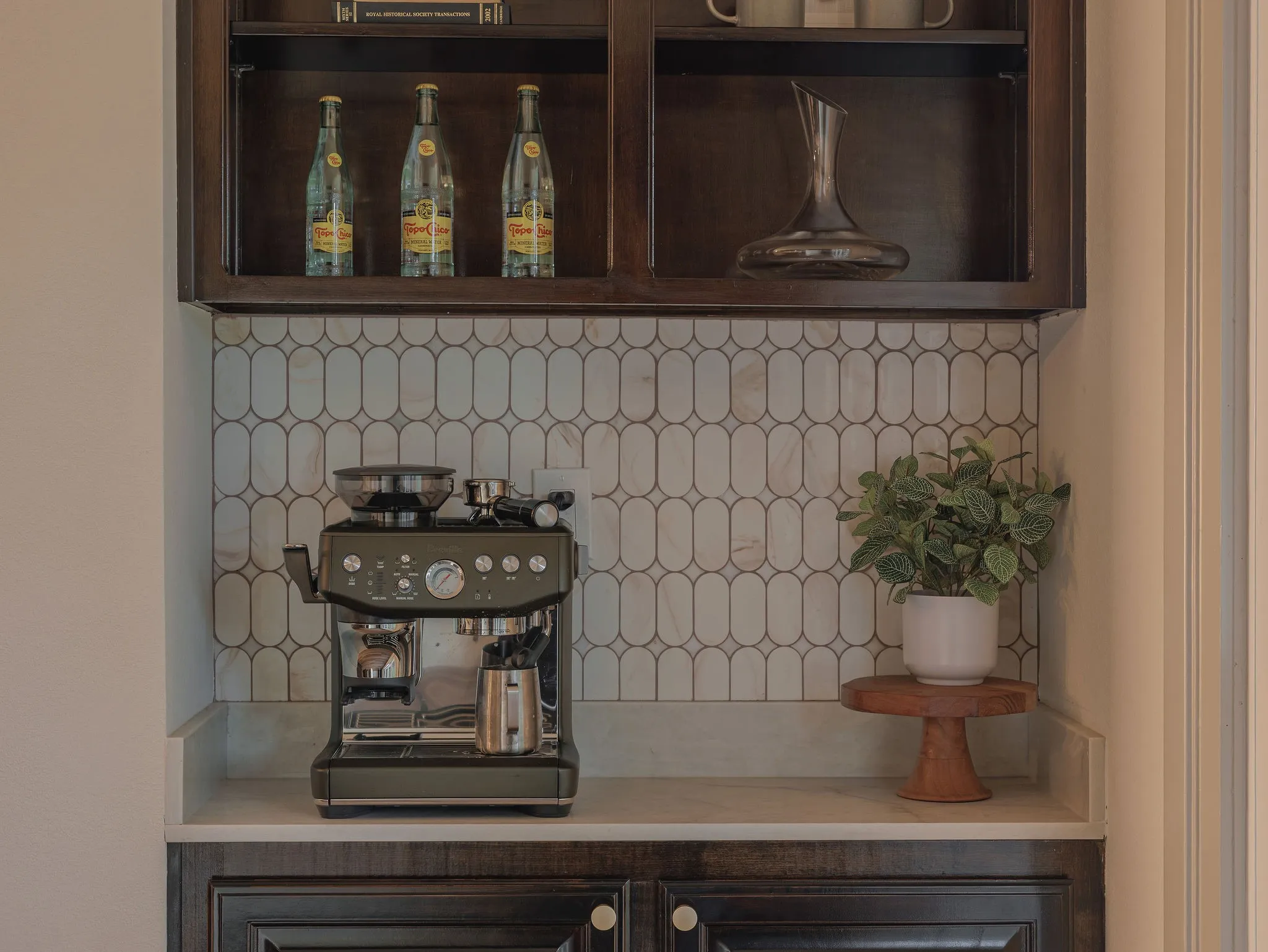 A dedicated coffee bar with custom cabinetry, quartz countertops and a statement tile backsplash adds both function and character.
