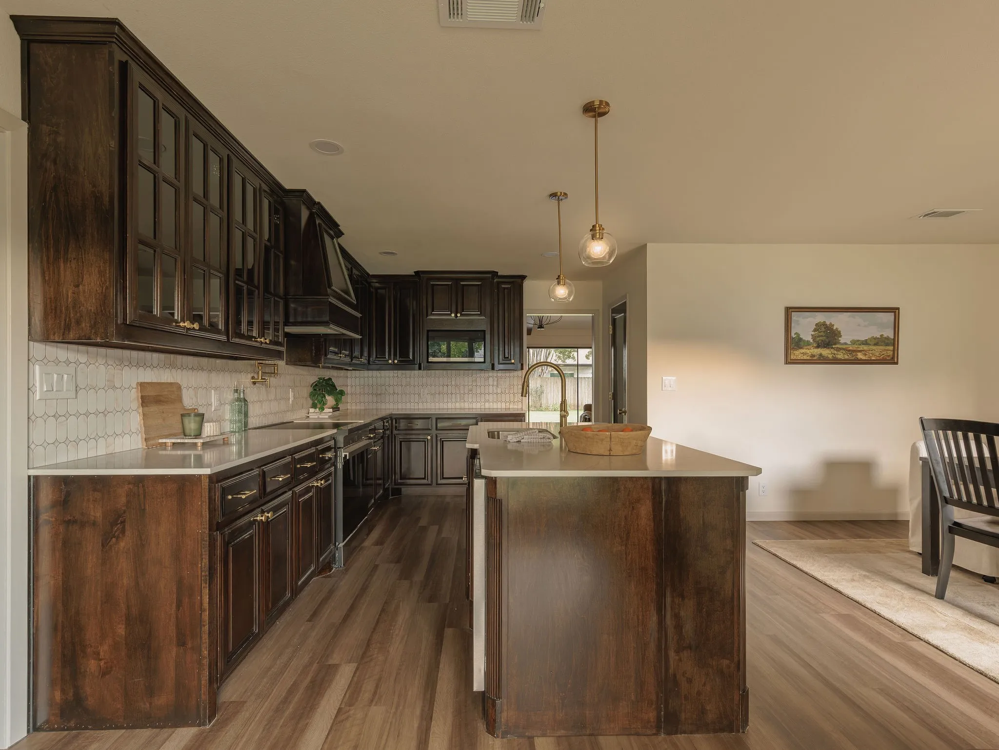 Custom dark walnut cabinetry, undercabinet lighting and quartz countertops bring warmth and depth to the thoughtfully redesigned kitchen.