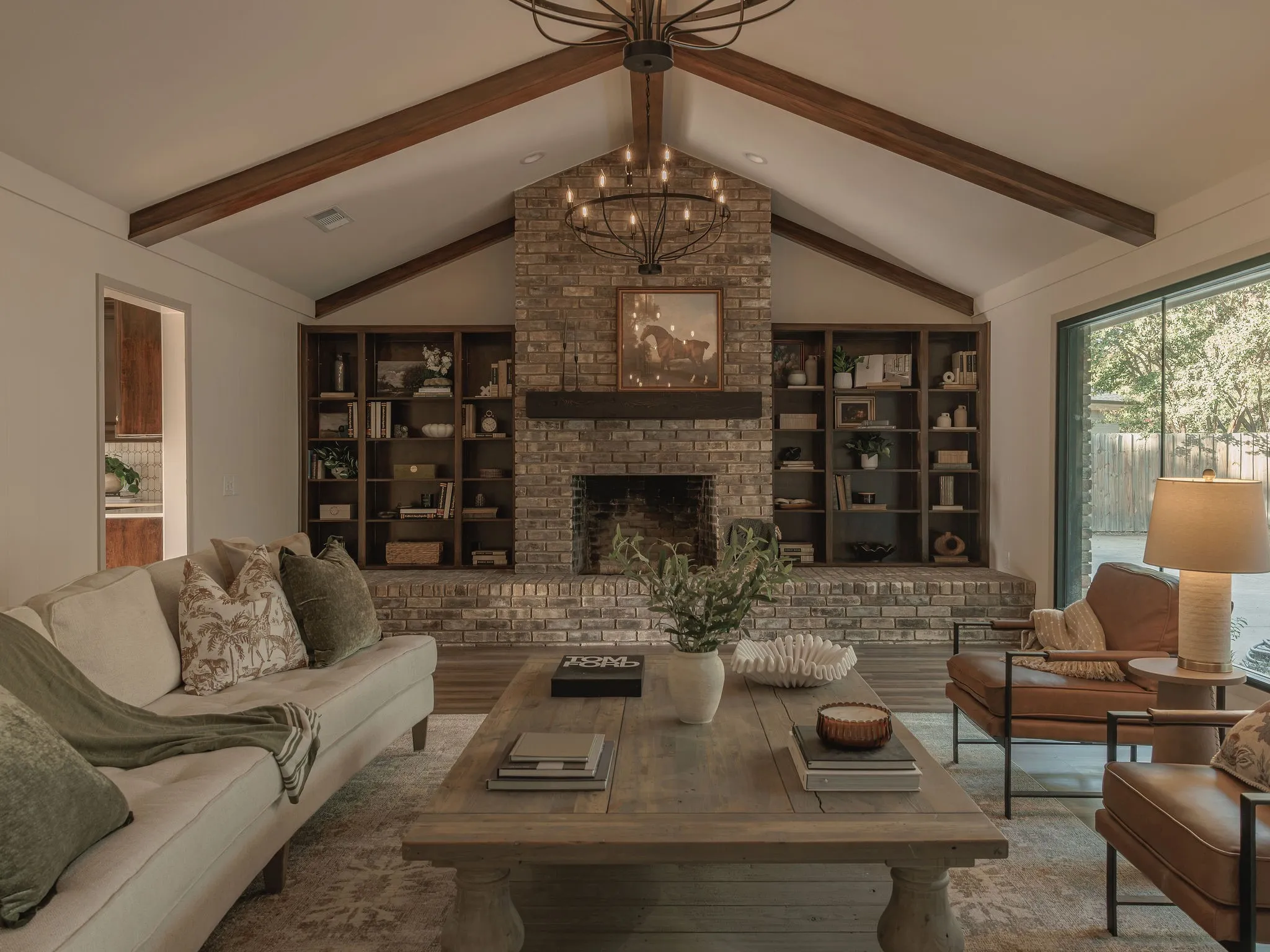 The main living room is anchored by a floor to ceiling brick fireplace, custom built ins, vaulted ceilings and exposed wood beams.