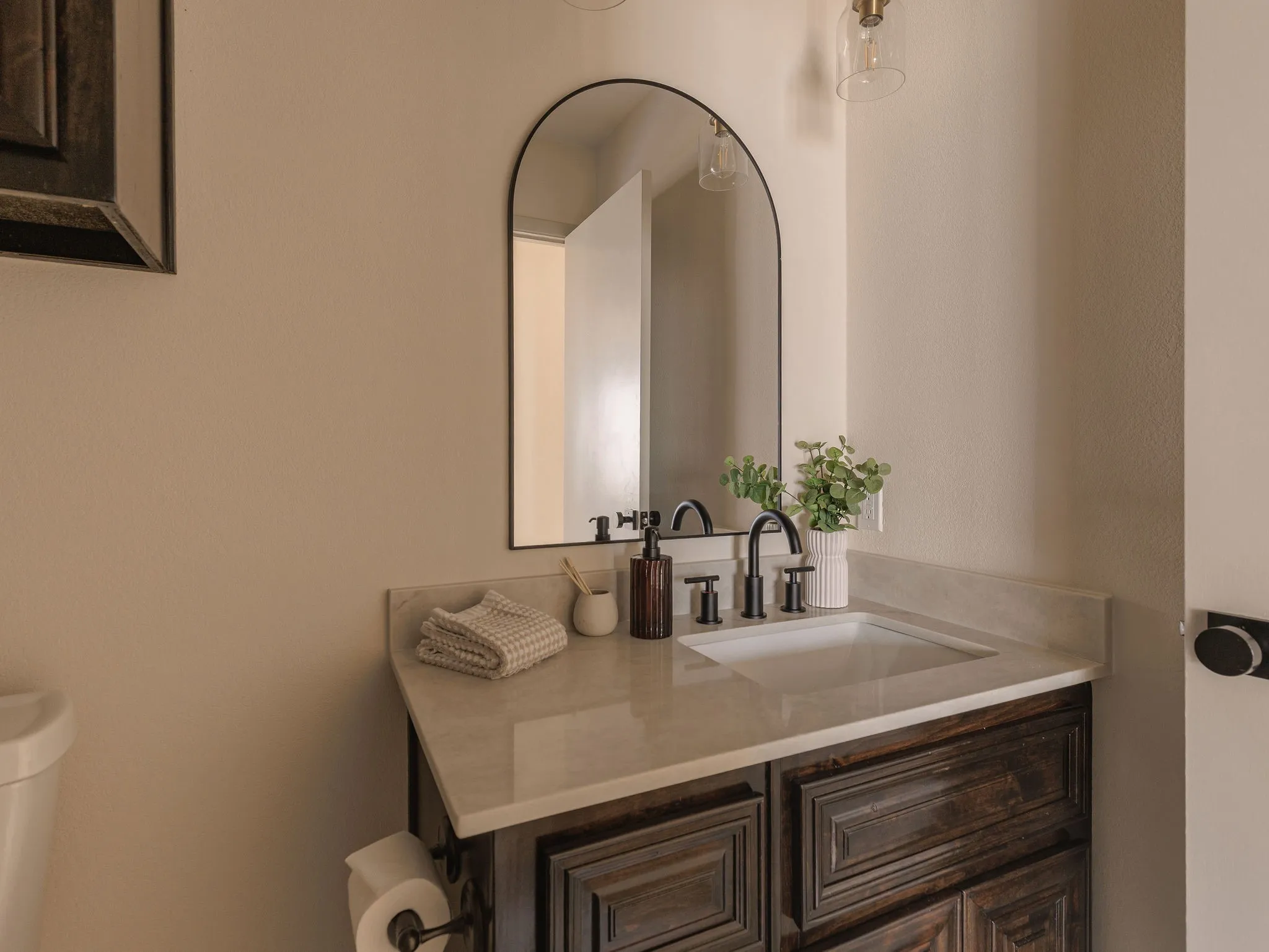 The updated secondary bath features a rich wood vanity, quartz countertop and matte black fixtures for a clean, collected finish.