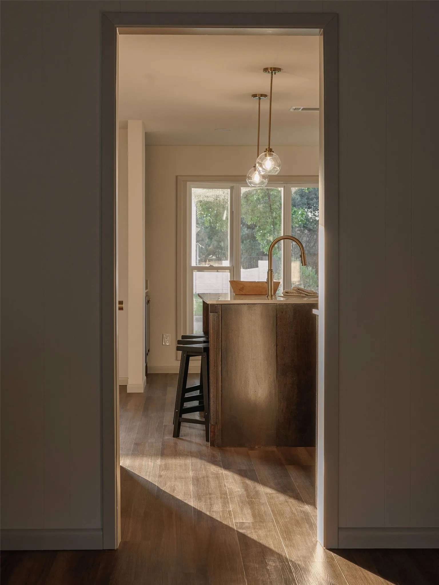Natural light moves through the home, highlighting the warm wood tones and thoughtful sightlines into the kitchen.