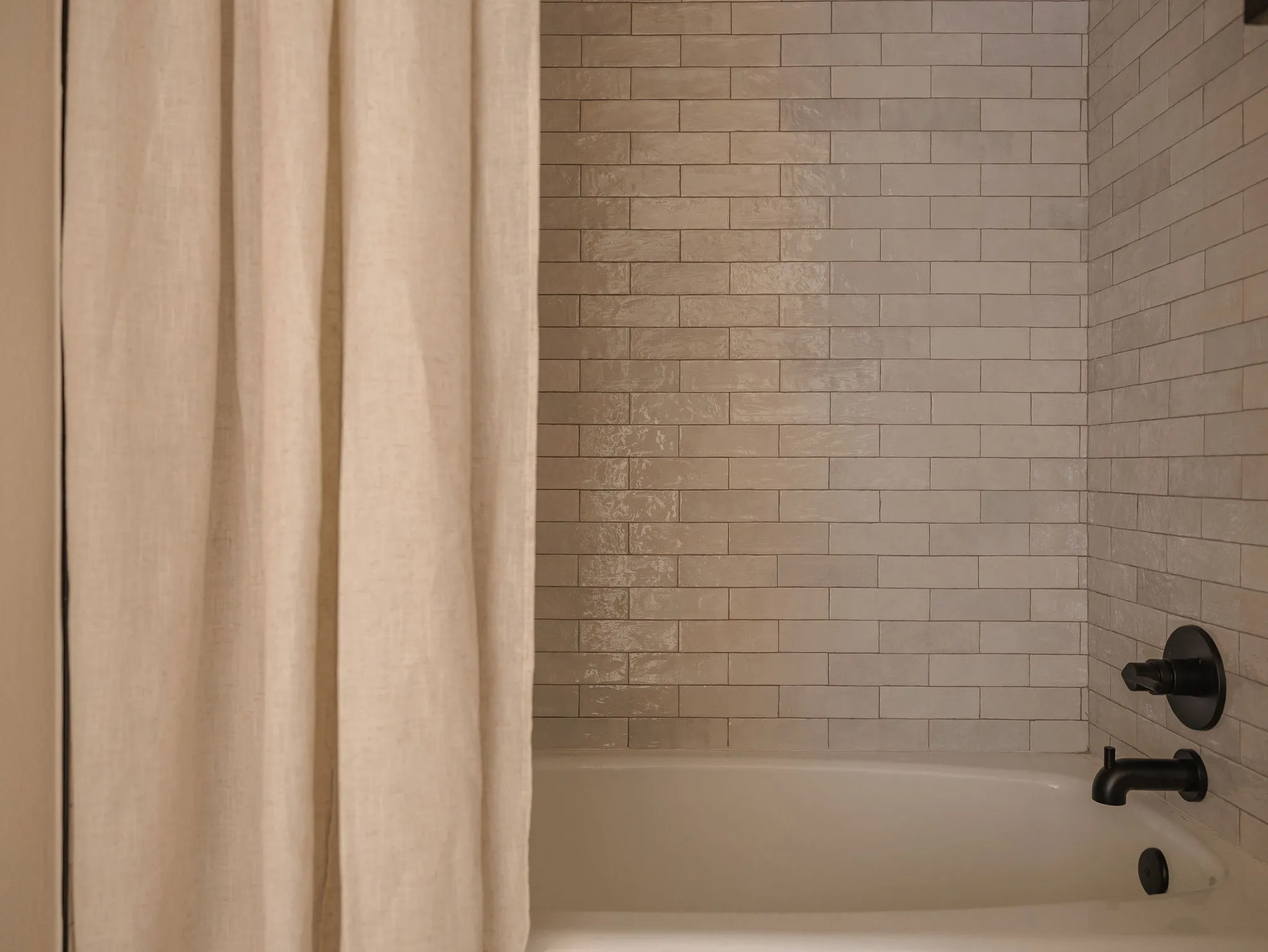 Textured tile surrounds the tub and shower, paired with matte black fixtures for a simple, elevated finish.